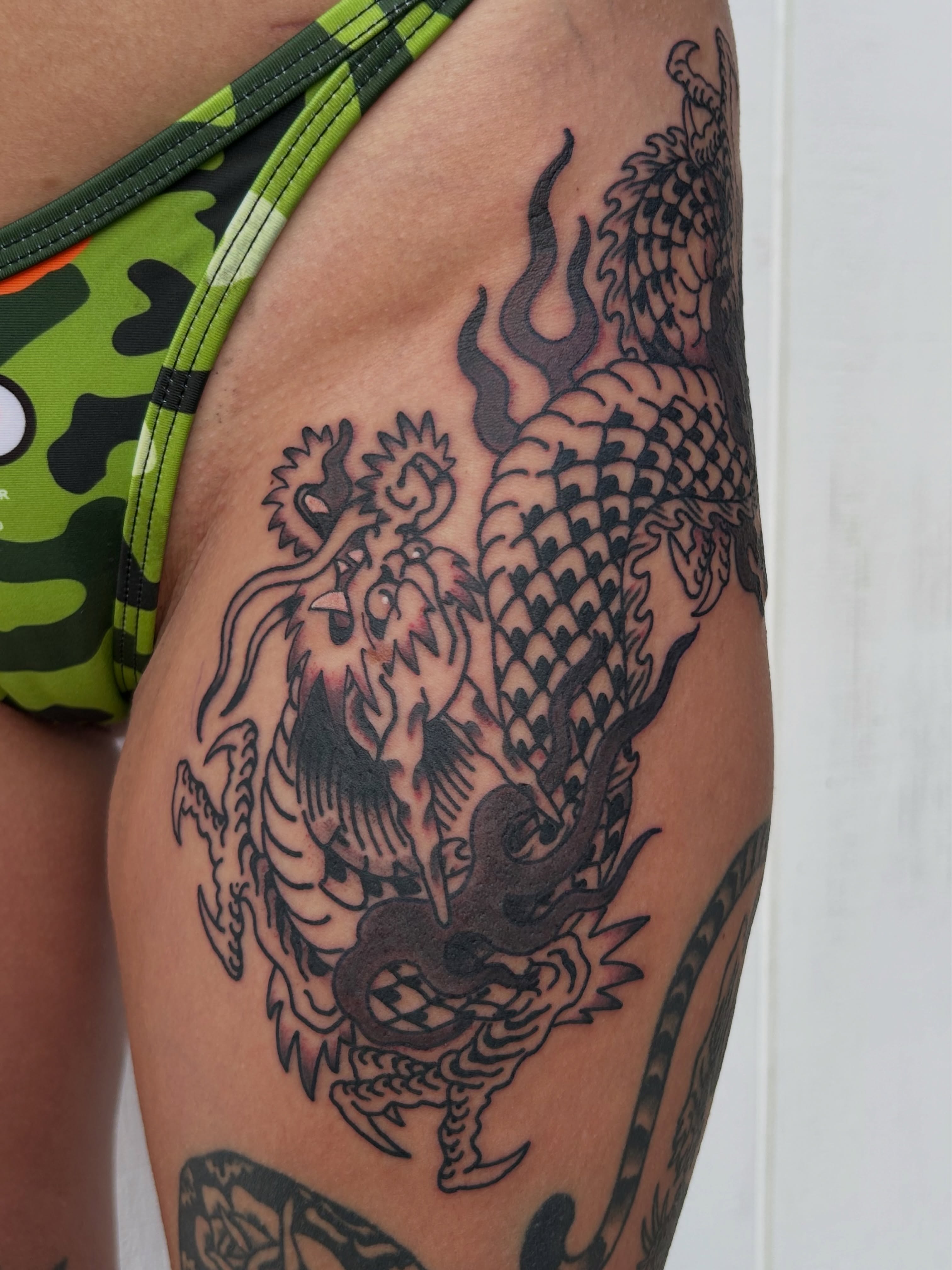 Dragon black and grey tattoo on the thigh by Lauren Alexandra