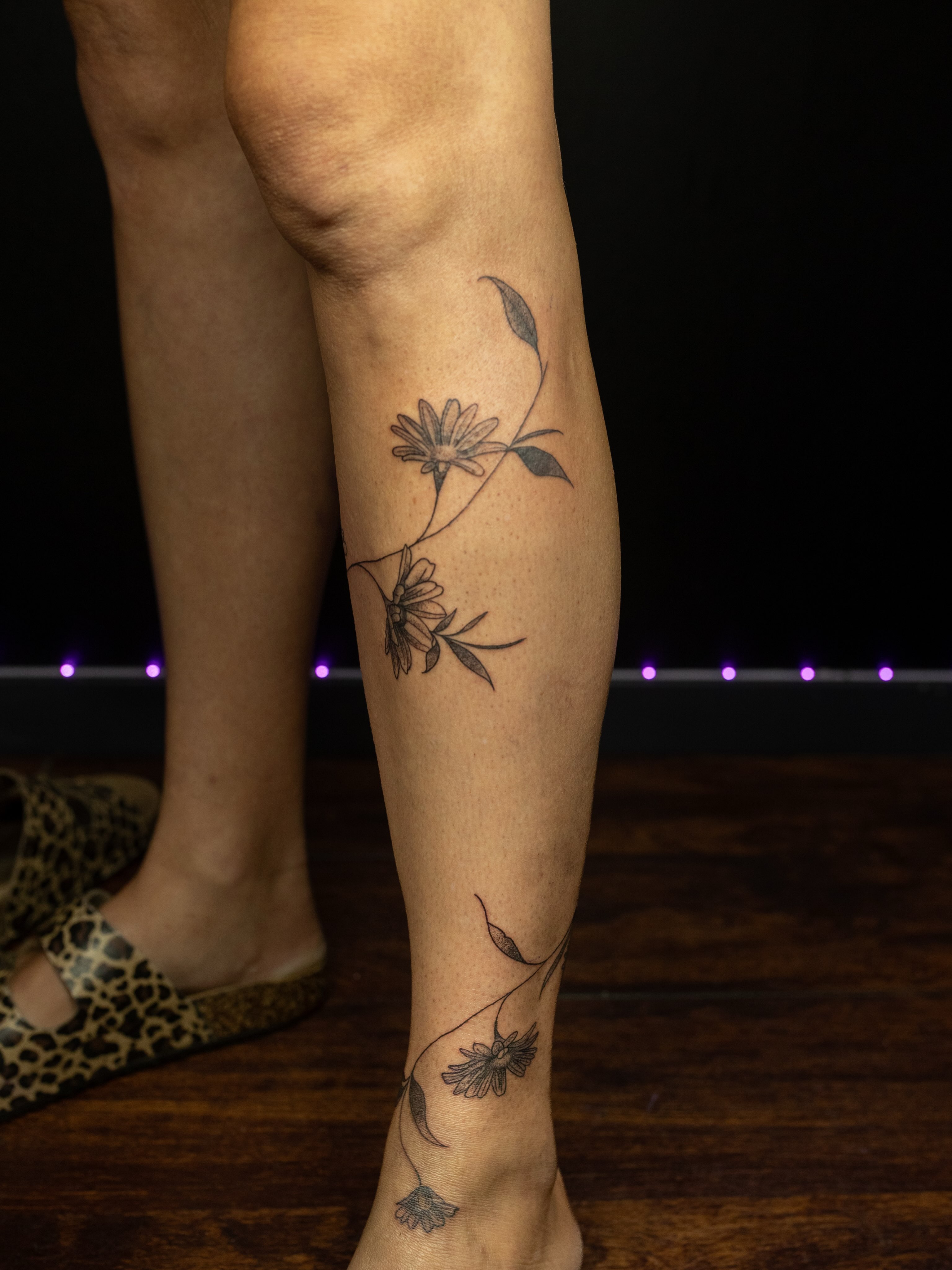 Daisies black and grey tattoo on the calf by Kelsie