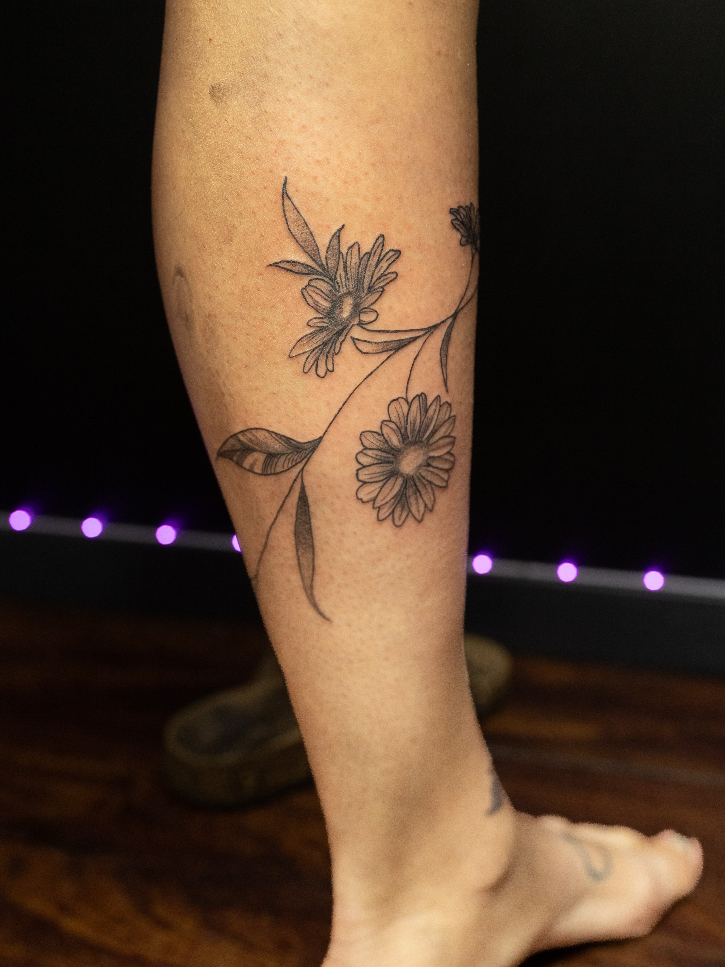 Daisies dotwork tattoo on the calf by Kelsie