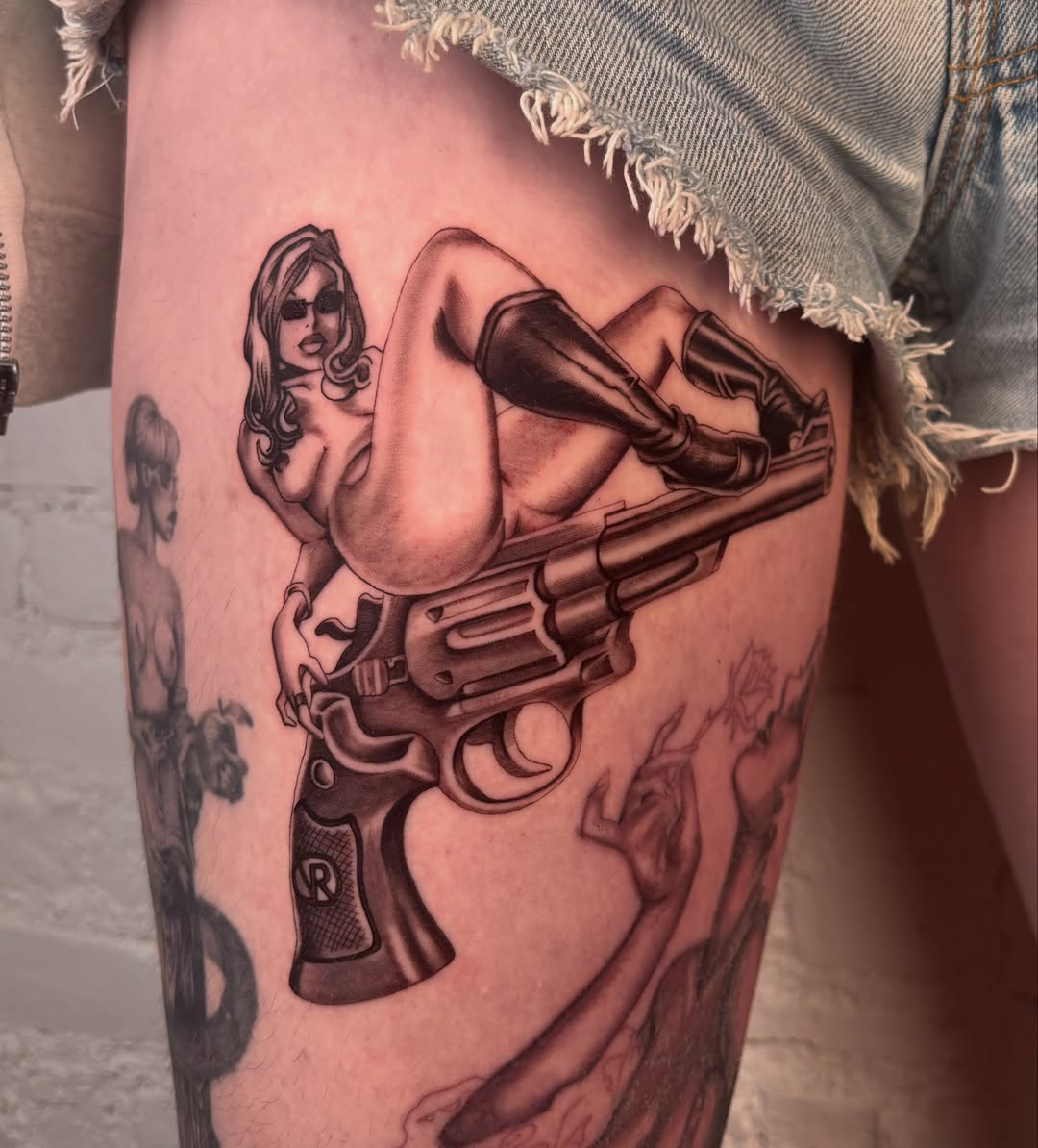 Gun and woman realism tattoo on the thigh by laura bianca