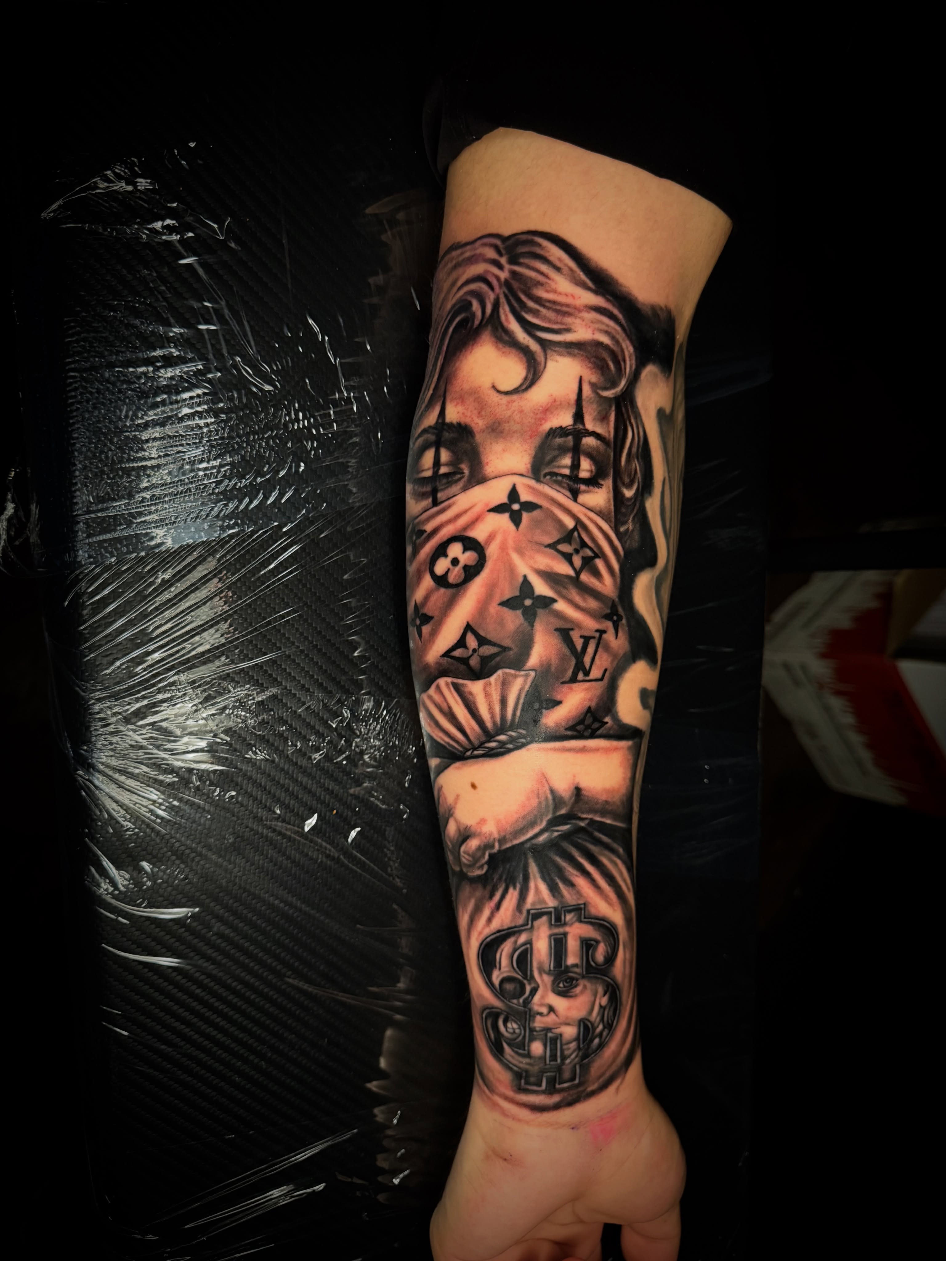 Mask with LV logos black and grey tattoo on the forearm by Dallas Tattoo Artist📍