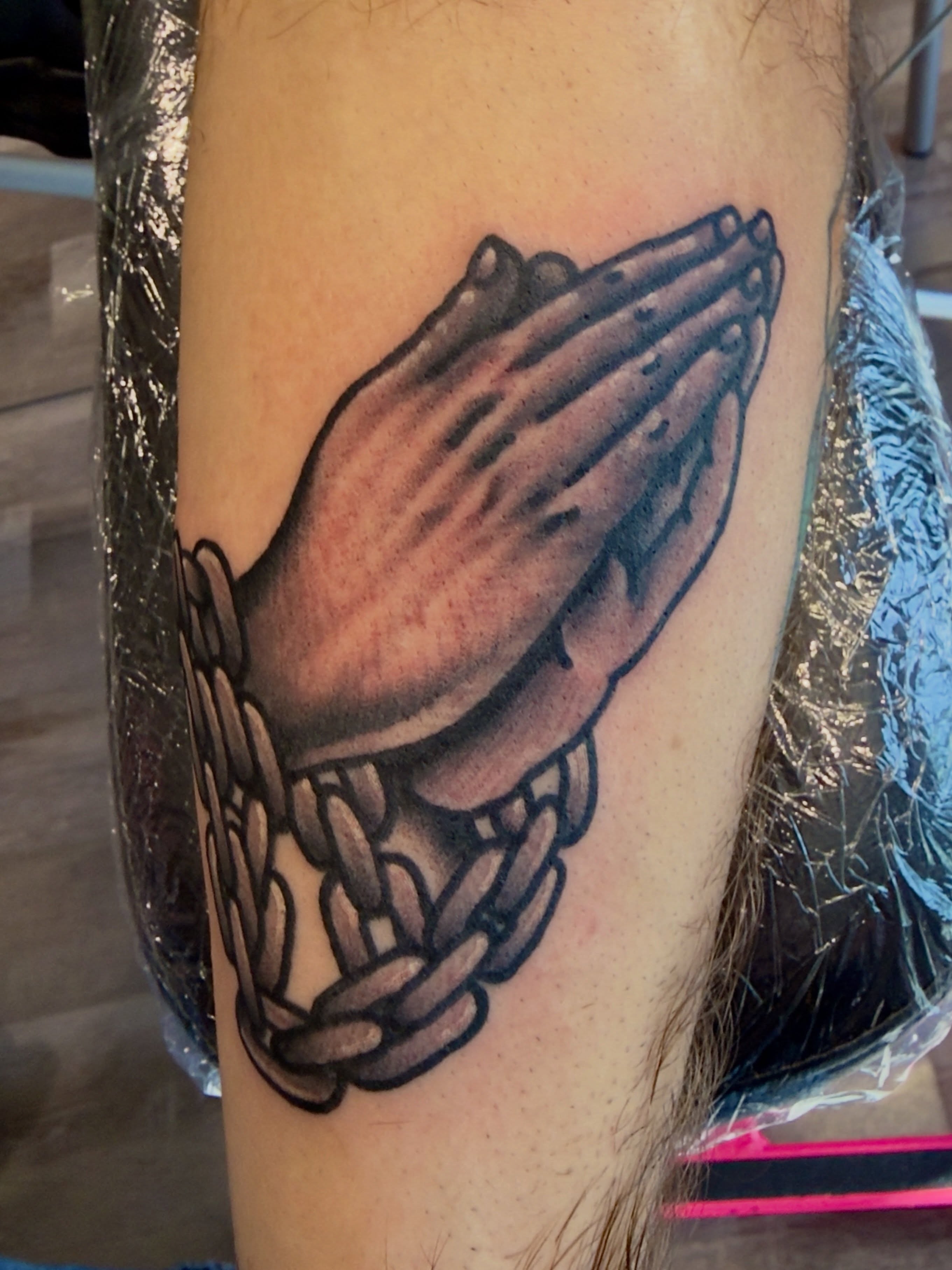 Praying hands black and grey tattoo on the forearm by Jimmy Kelley