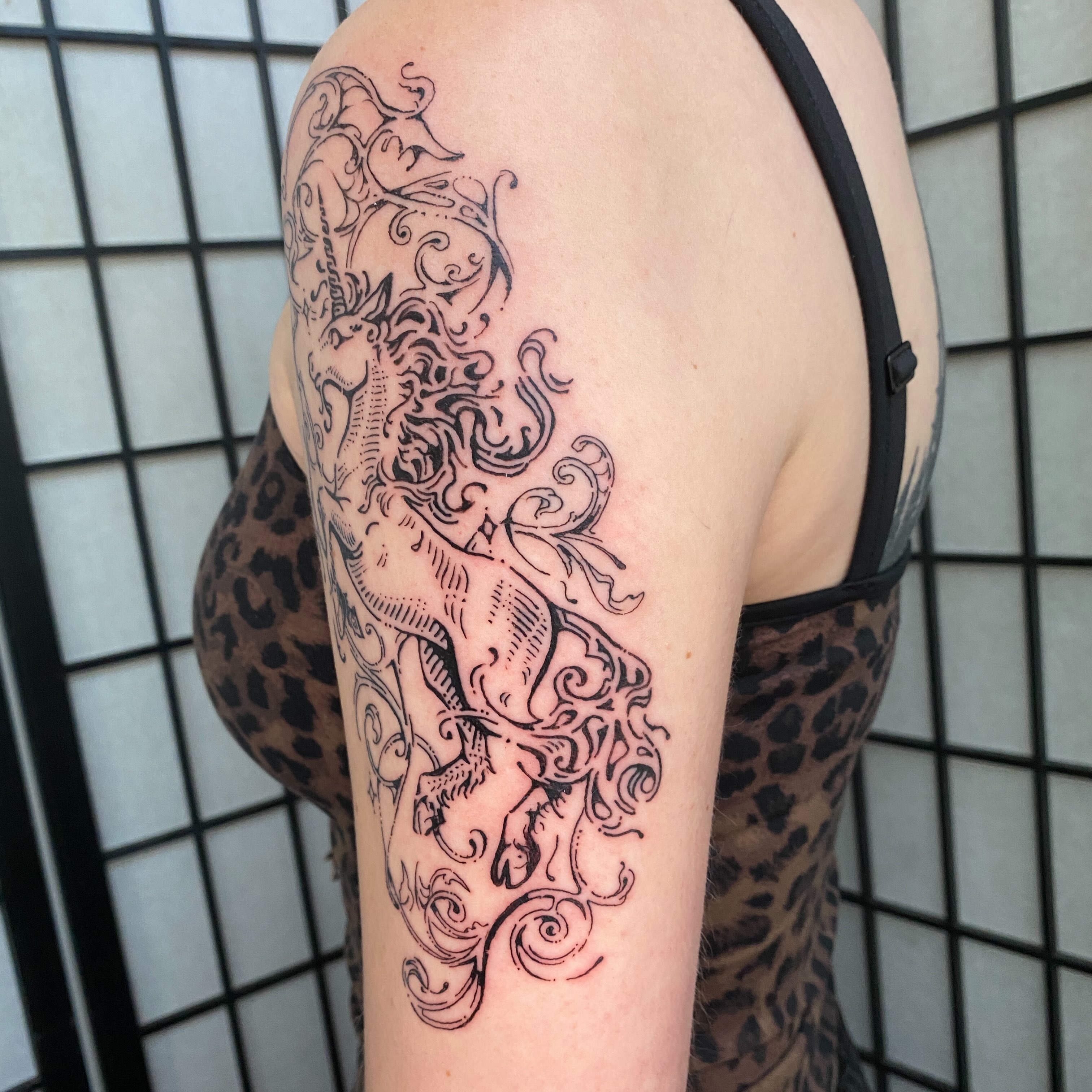 Unicorns black and grey tattoo on the upper arm by Clara