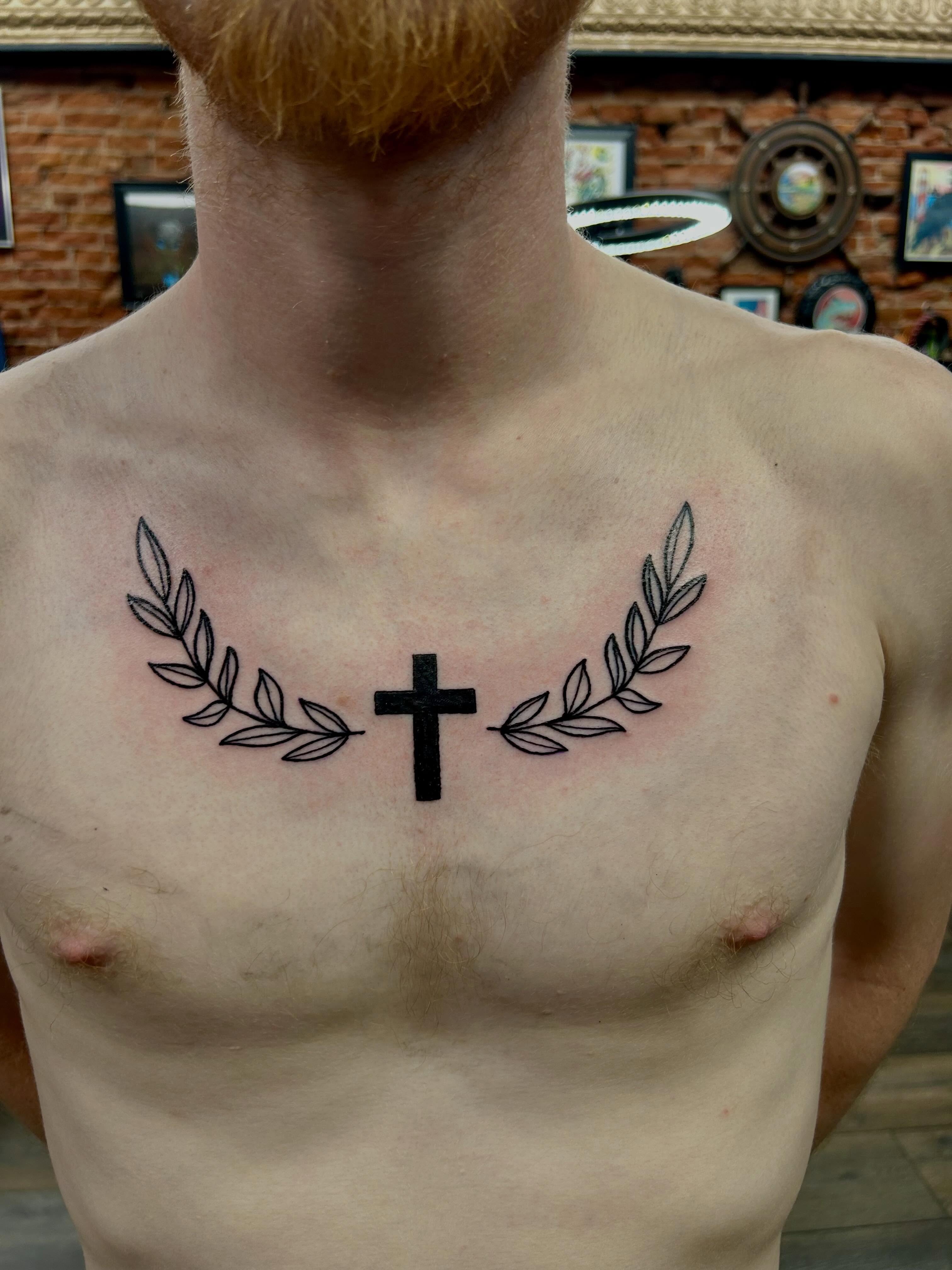 Cross with laurel wreath black and grey tattoo on the chest by Bjorn Bjornstad, Dubuque, Iowa