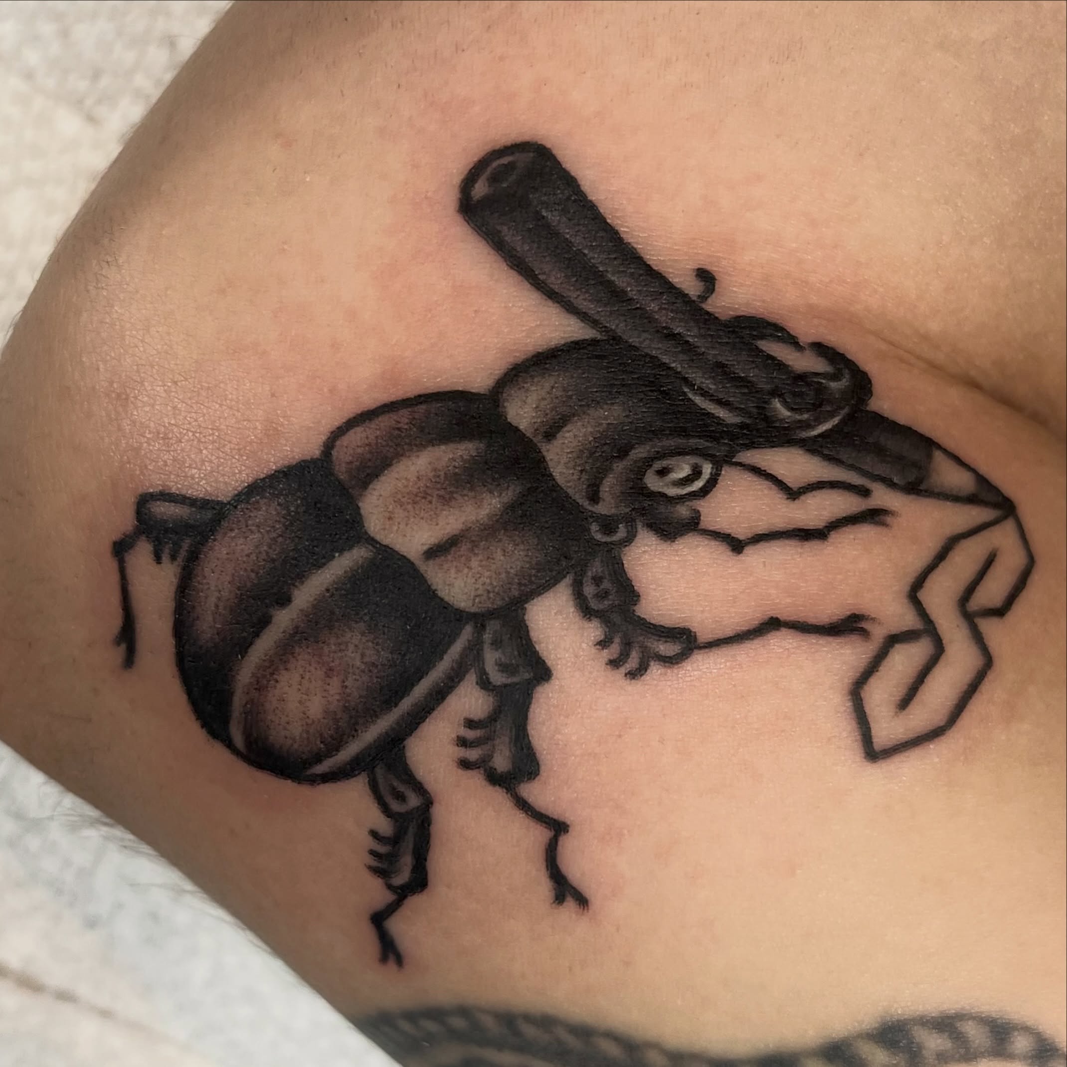 Scarab beetle black and grey tattoo on the thigh by Téa Fish