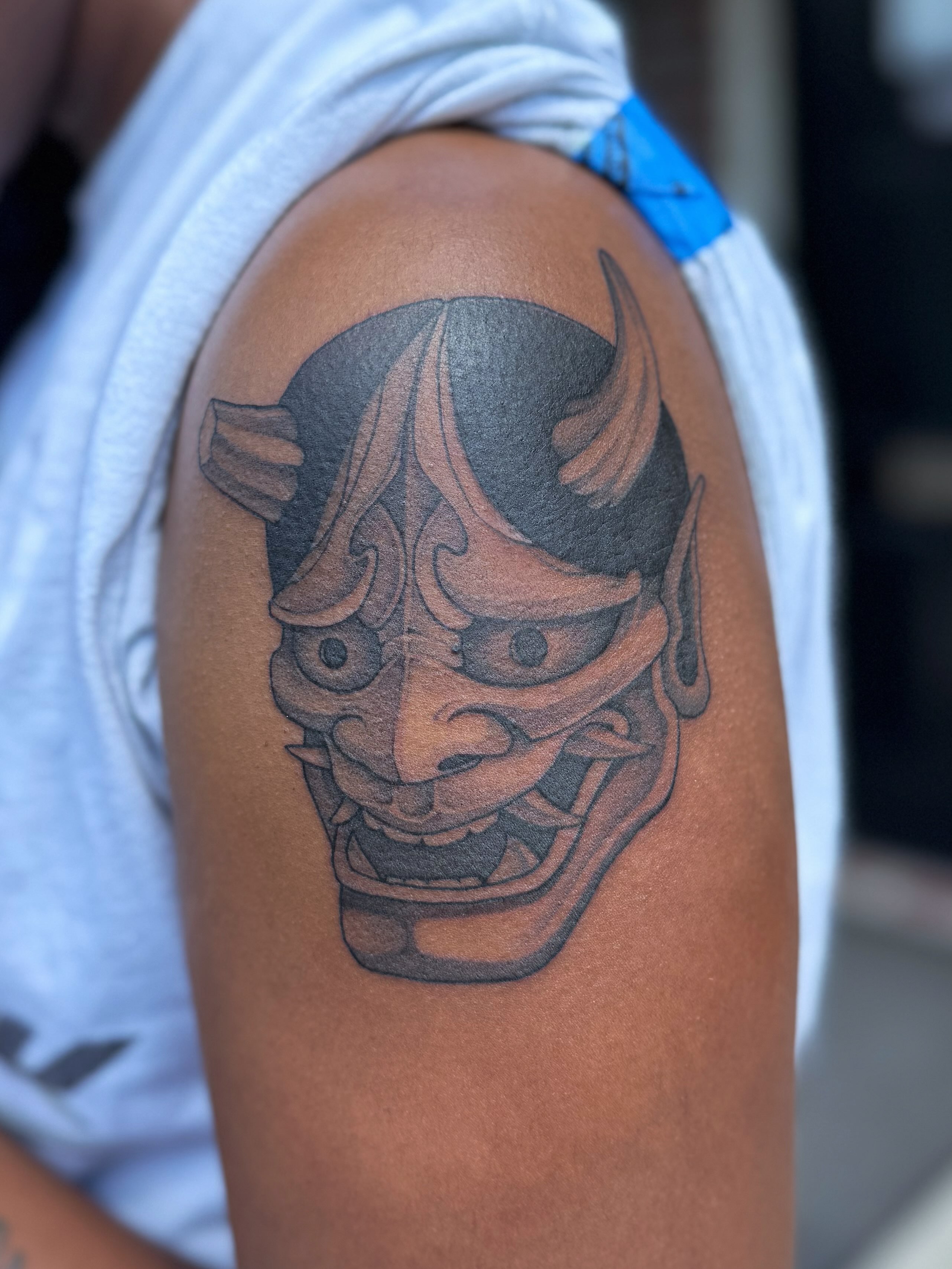 Demon mask black and grey tattoo on the shoulder by 𝔍𝔞𝔯𝔢𝔡 𝔞𝔩𝔩𝔢𝔫