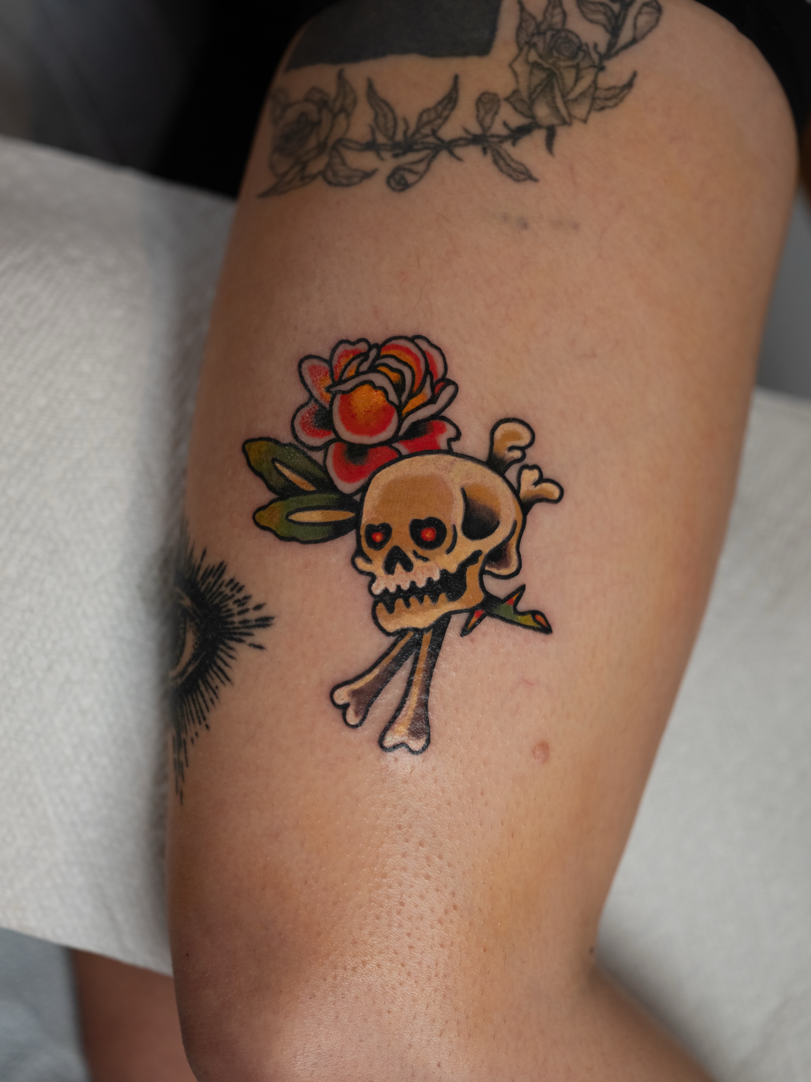 Skull and crossbones with flower American traditional tattoo on the forearm by Dylan Coverdale