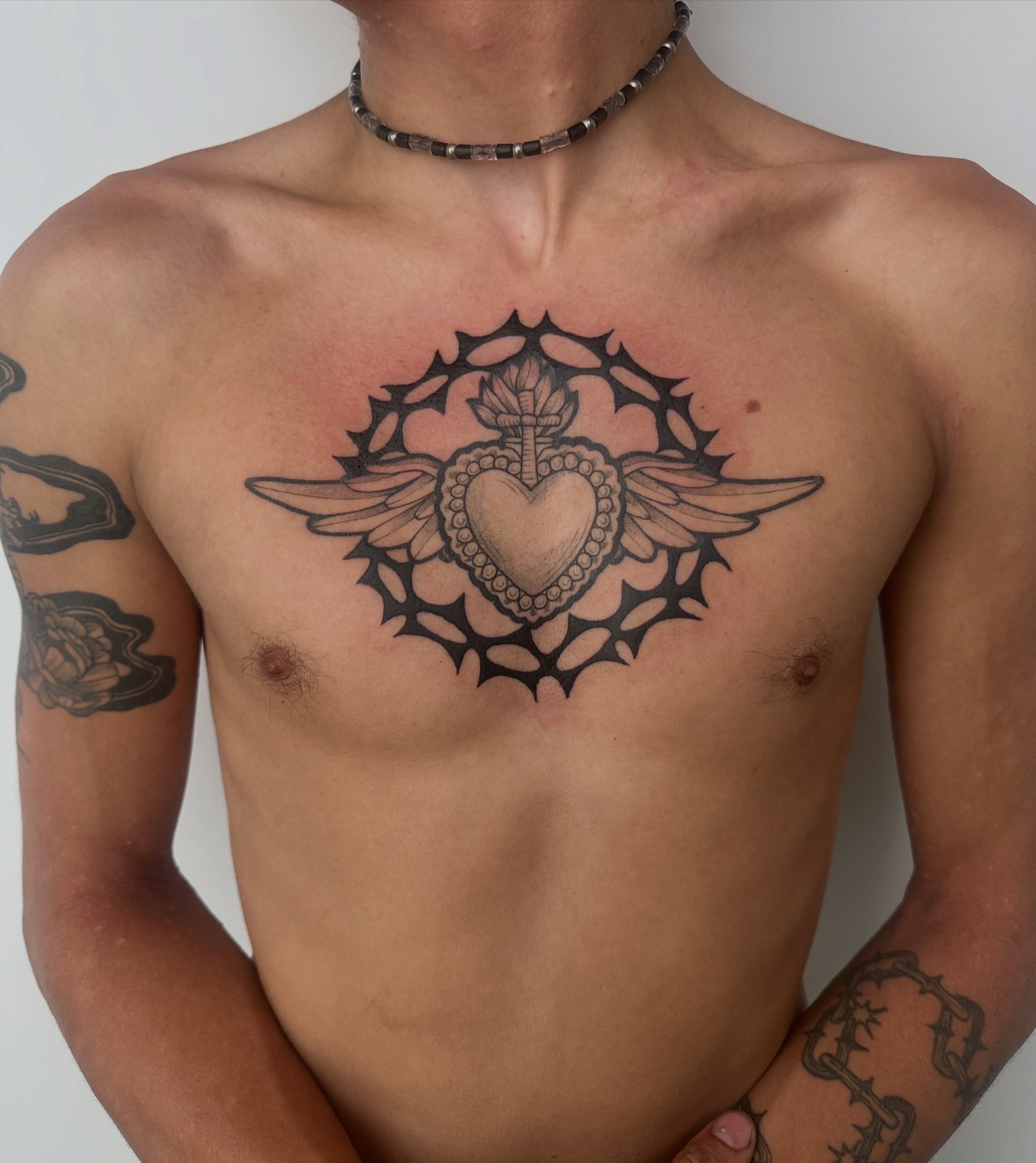 Heart with wings black and grey tattoo on the chest by Nia Malone (Knee-Uh)