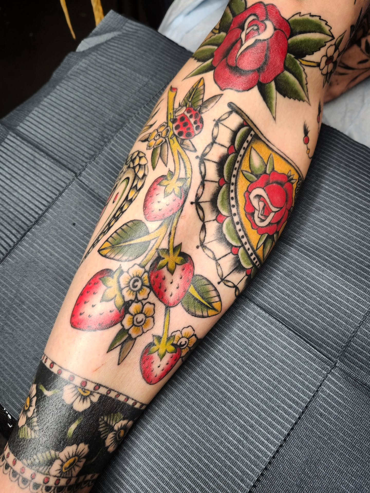 Strawberries and roses American traditional tattoo on the forearm by Kelly Zito