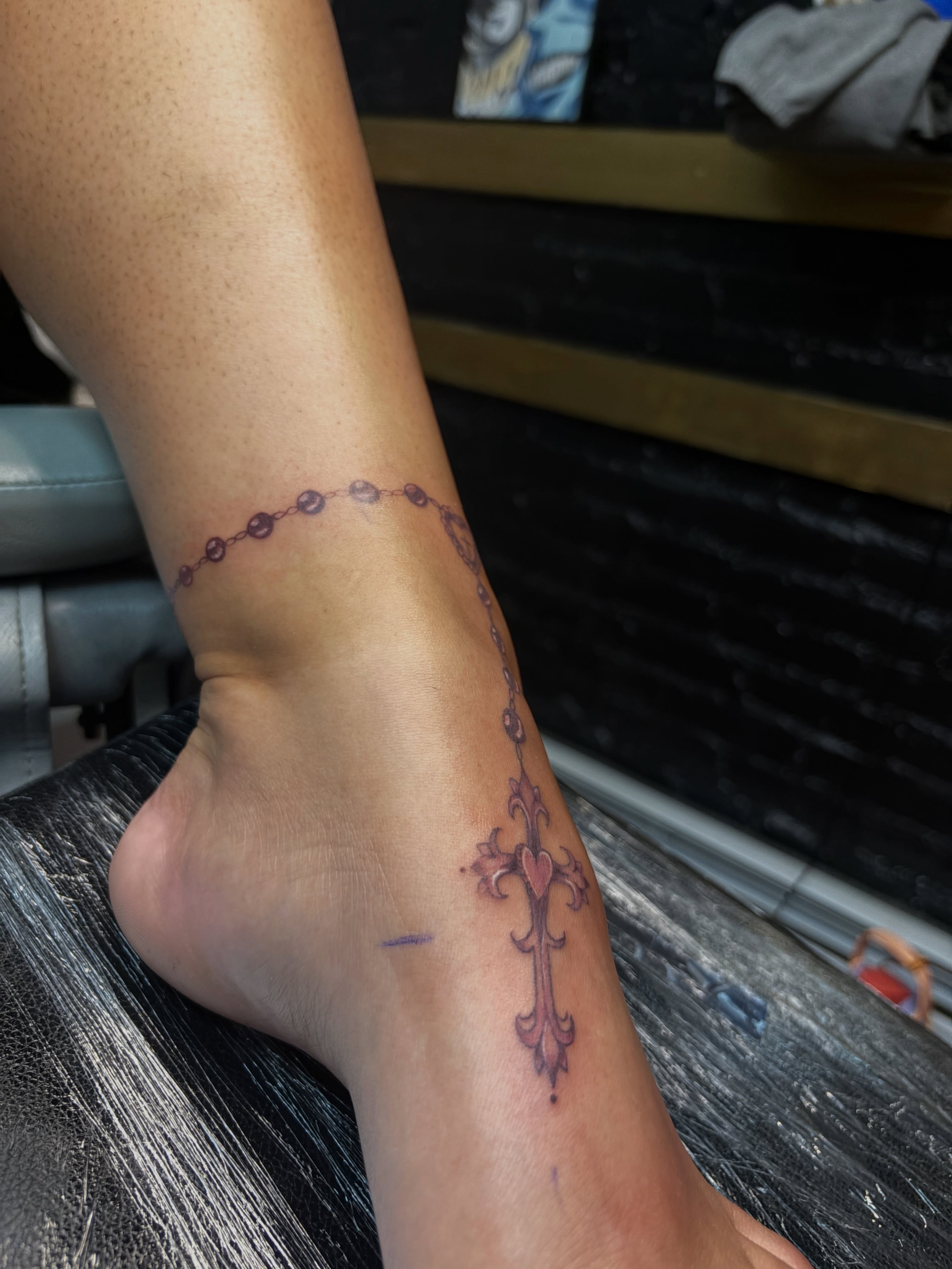 Rosary and cross black and grey tattoo on the forearm by Destineé