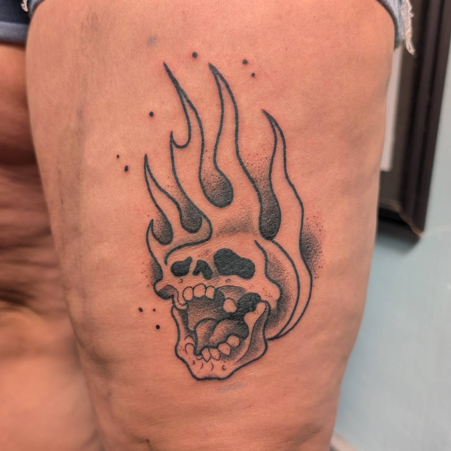 Flaming skull black and grey tattoo on the thigh by norn noszka