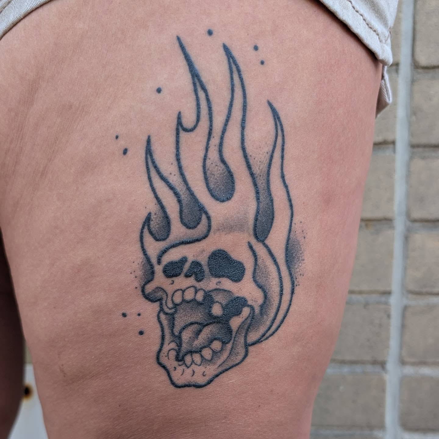 Flaming skull black and grey tattoo on the thigh by norn noszka