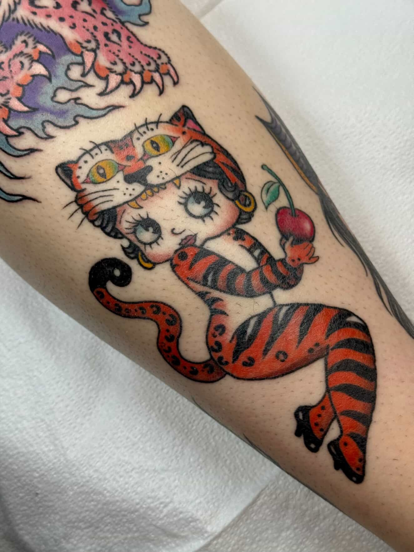 Cat with cherries American traditional tattoo on the forearm by Hayley Hendrick