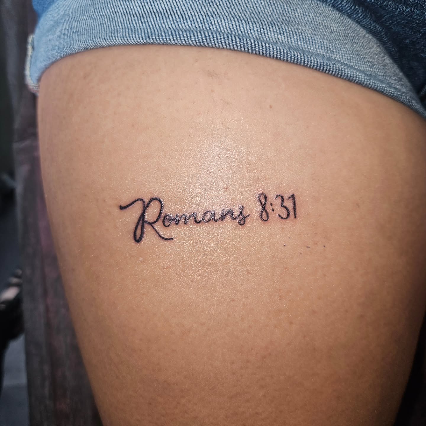 Romans 8:31 lettering script tattoo on the thigh by Mischief π€