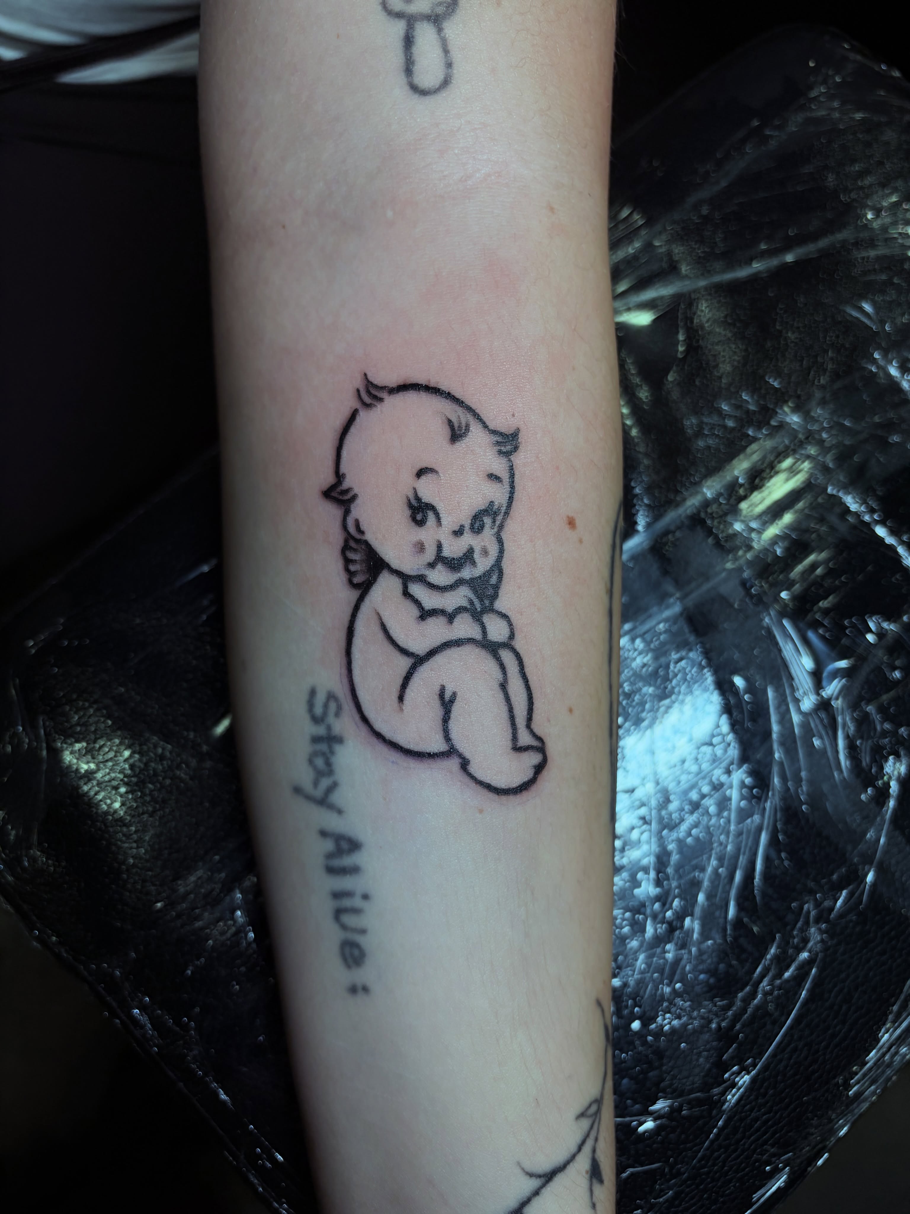 Baby black and grey tattoo on the forearm by Carlen Gil