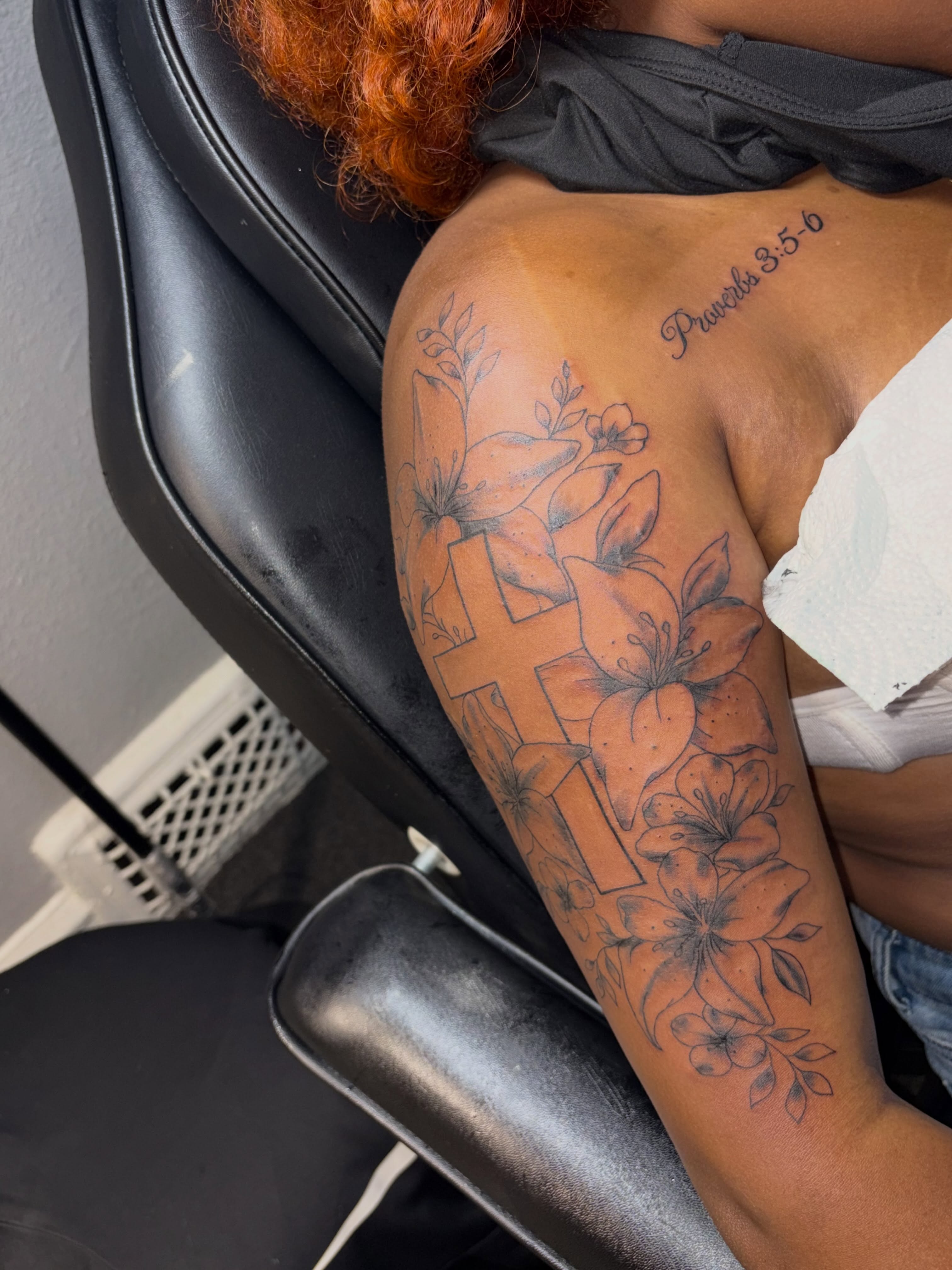 Cross and flowers black and grey tattoo on the upper arm by 216 Tattoos 🥰