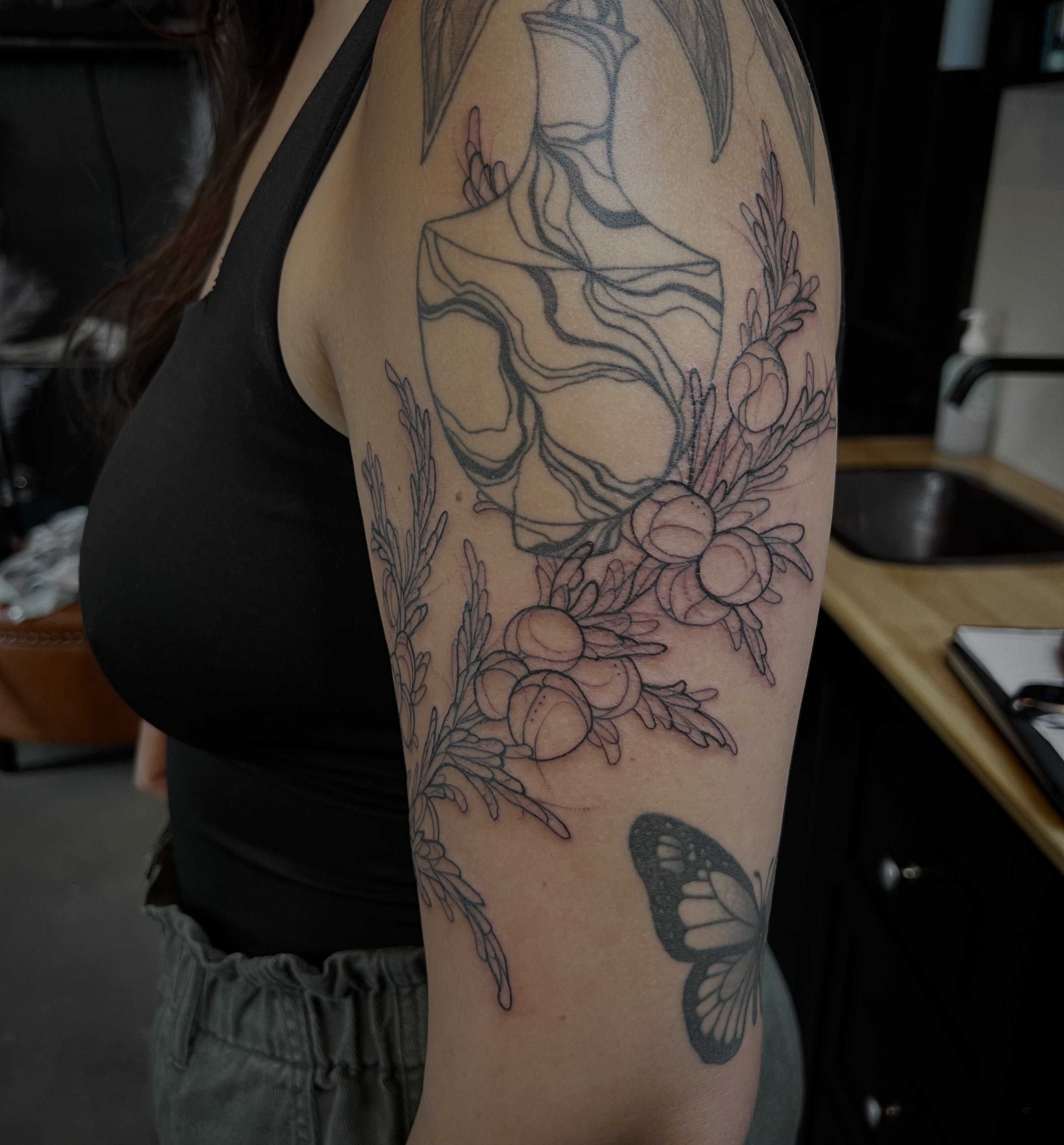 Skull and floral arrangement black and grey tattoo on the forearm by Amanda Leitch
