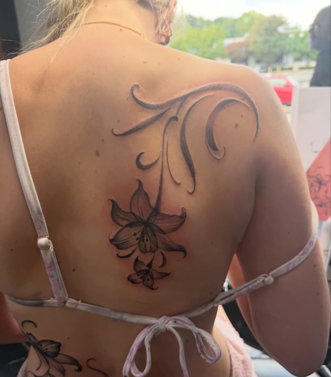Lily and swirls black and grey tattoo on the back by Jinx Ryder