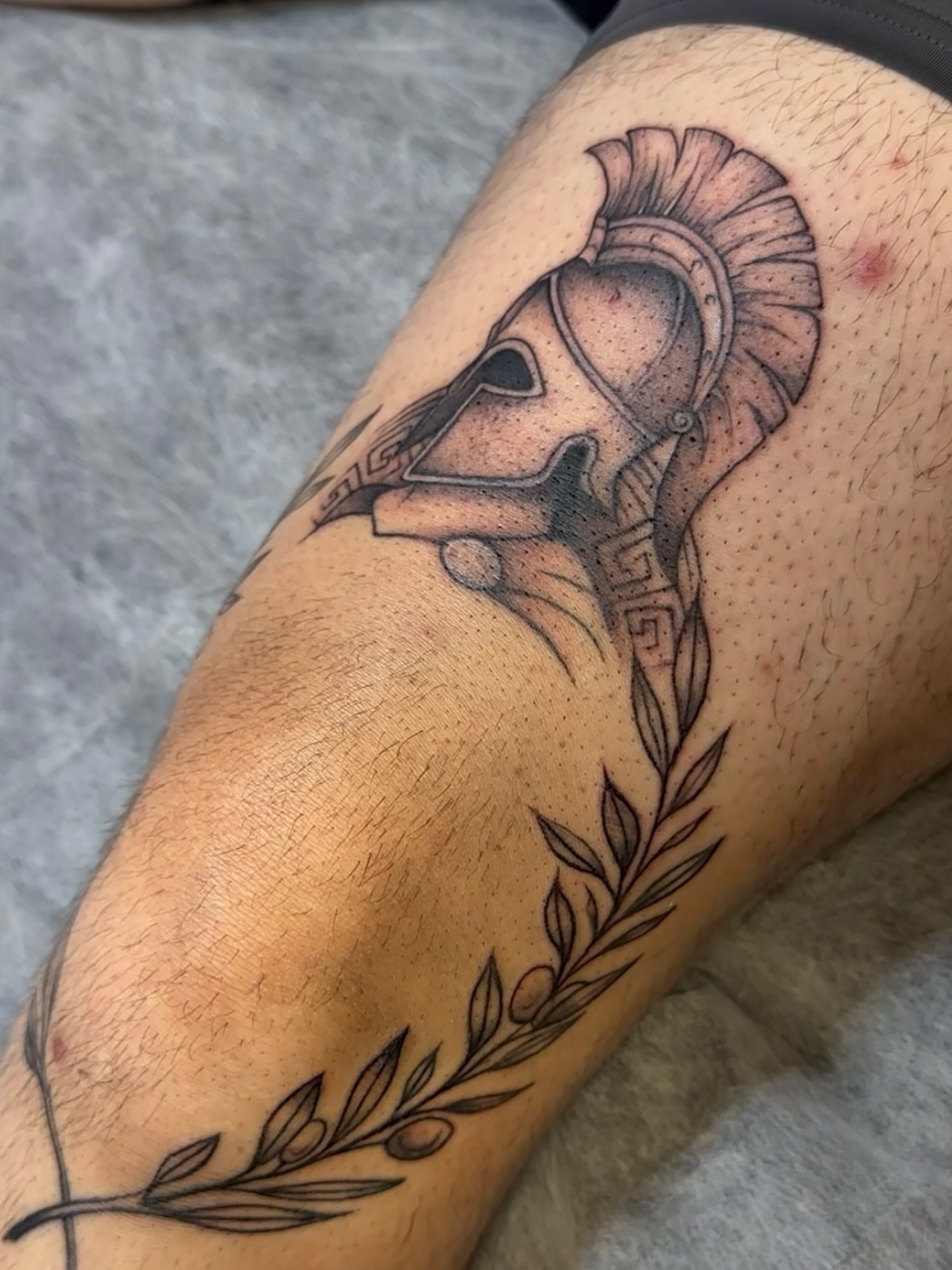 Spartan helmet black and grey tattoo on the forearm by Jocelyn