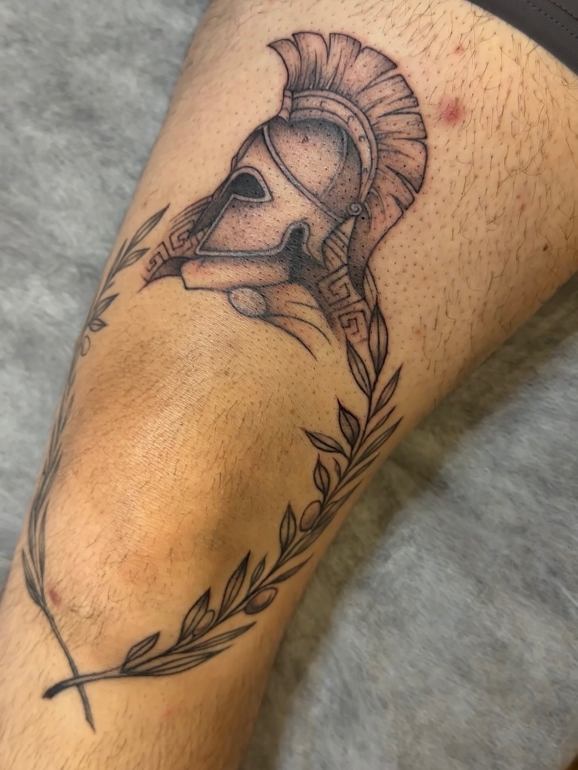 Spartan helmet black and grey tattoo on the forearm by Jocelyn