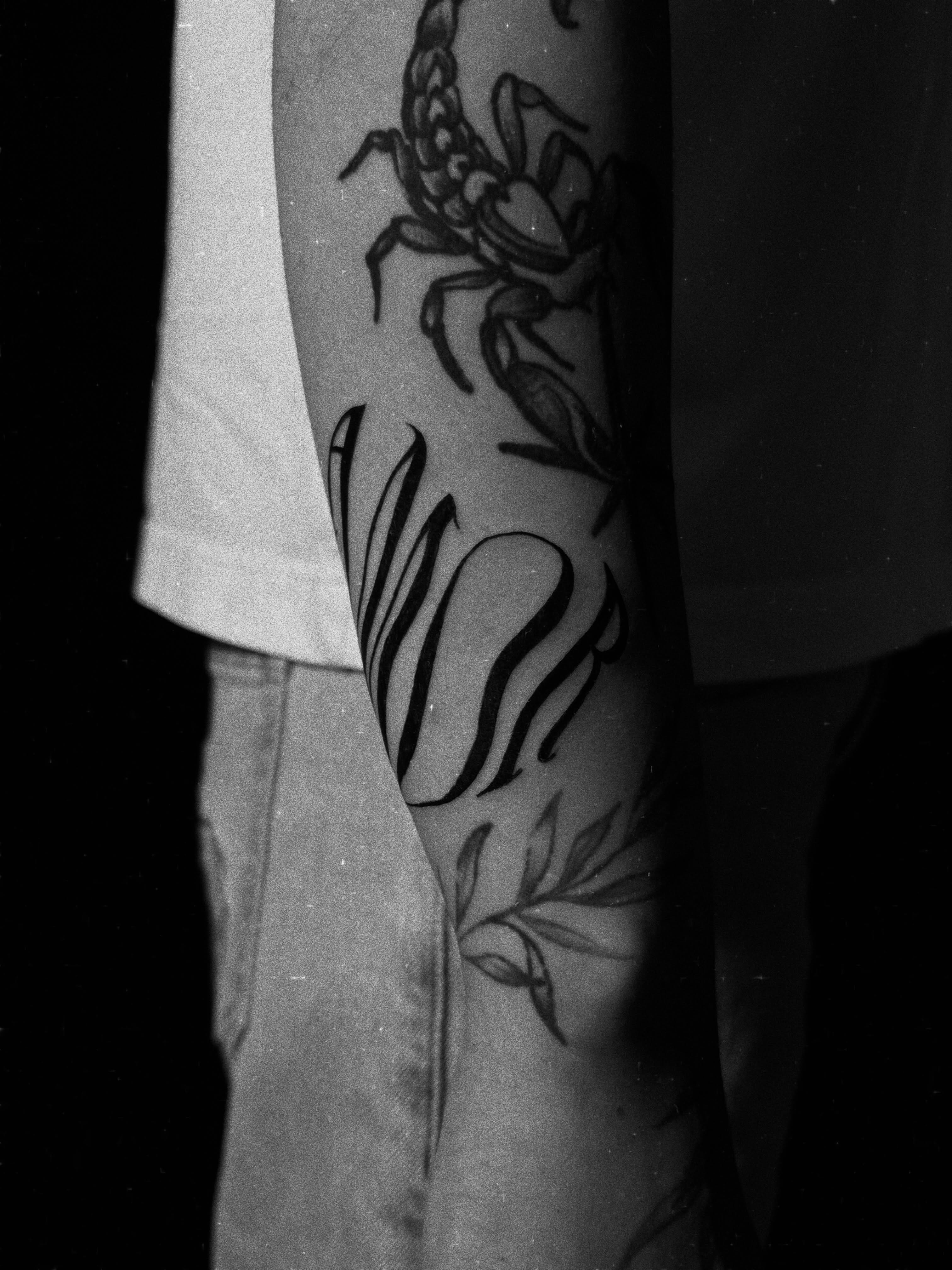 Scorpion and tulip black and grey tattoo on the forearm by Messias Tattoo Artist