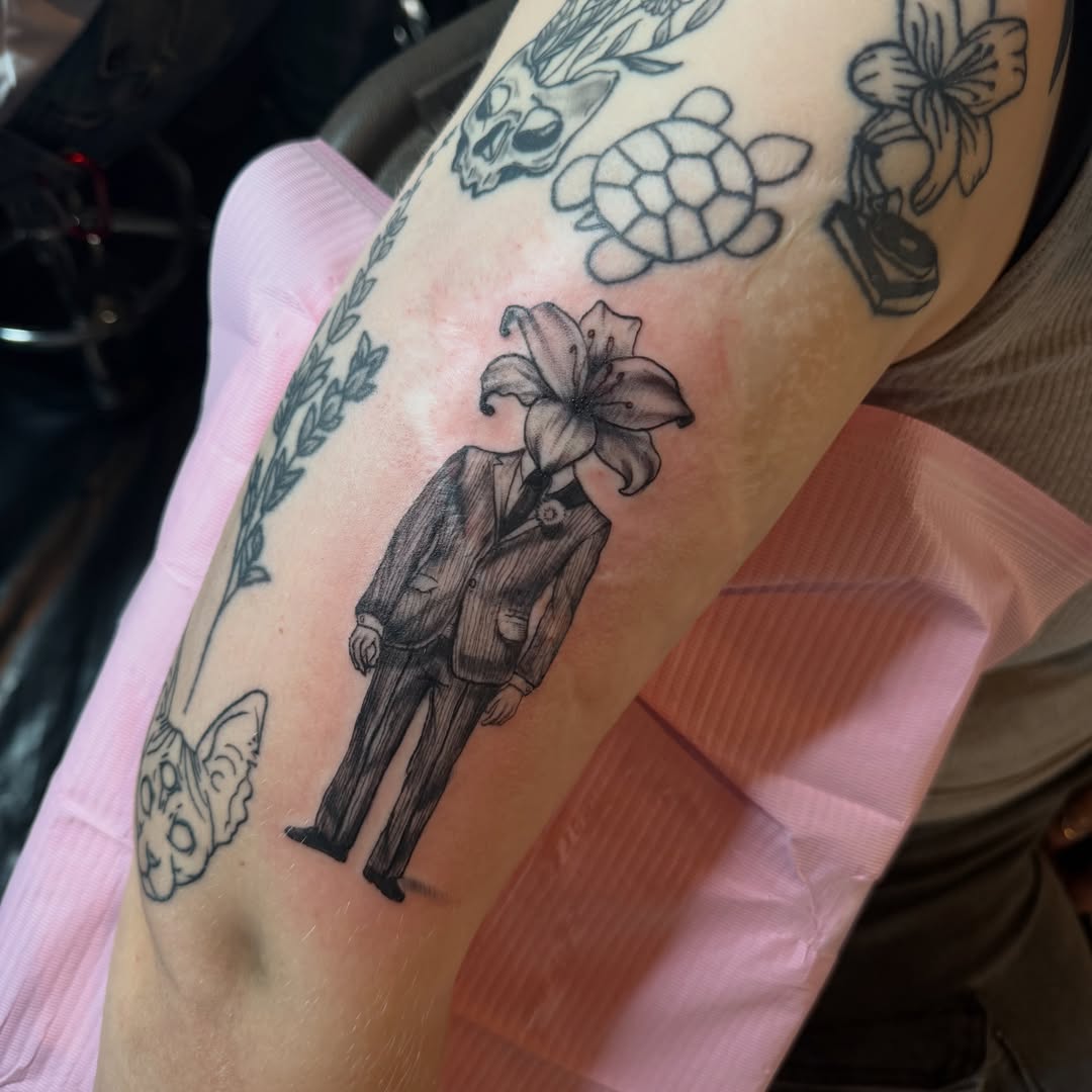 Man with flower head black and grey tattoo on the forearm by Nina Nichole