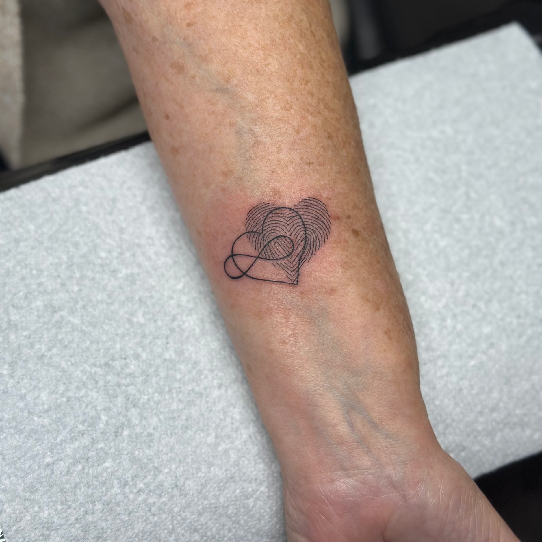 Fingerprint heart geometric tattoo on the forearm by Mandy Kaur