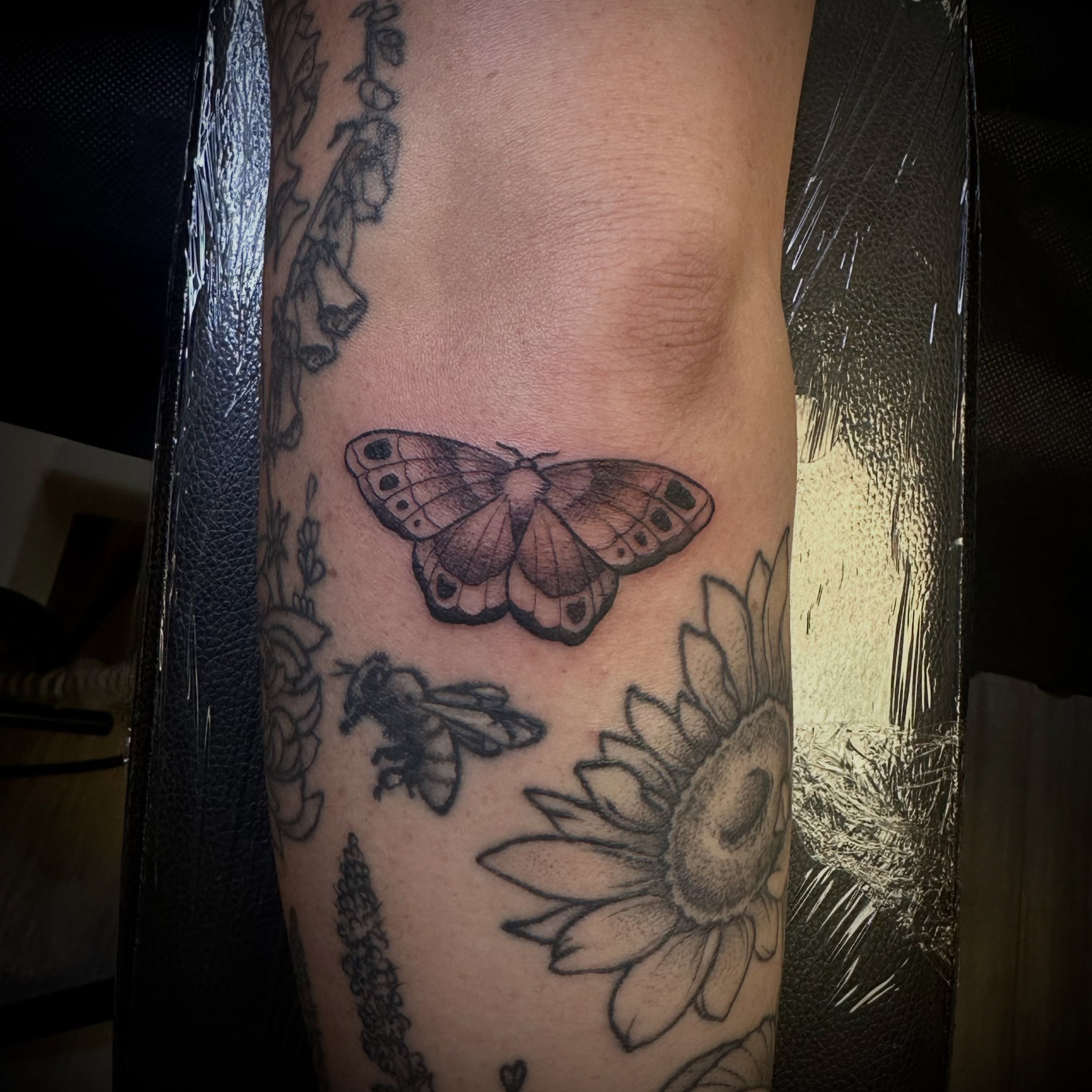 Butterfly and sunflower black and grey tattoo on the forearm by Zoe Arrigo