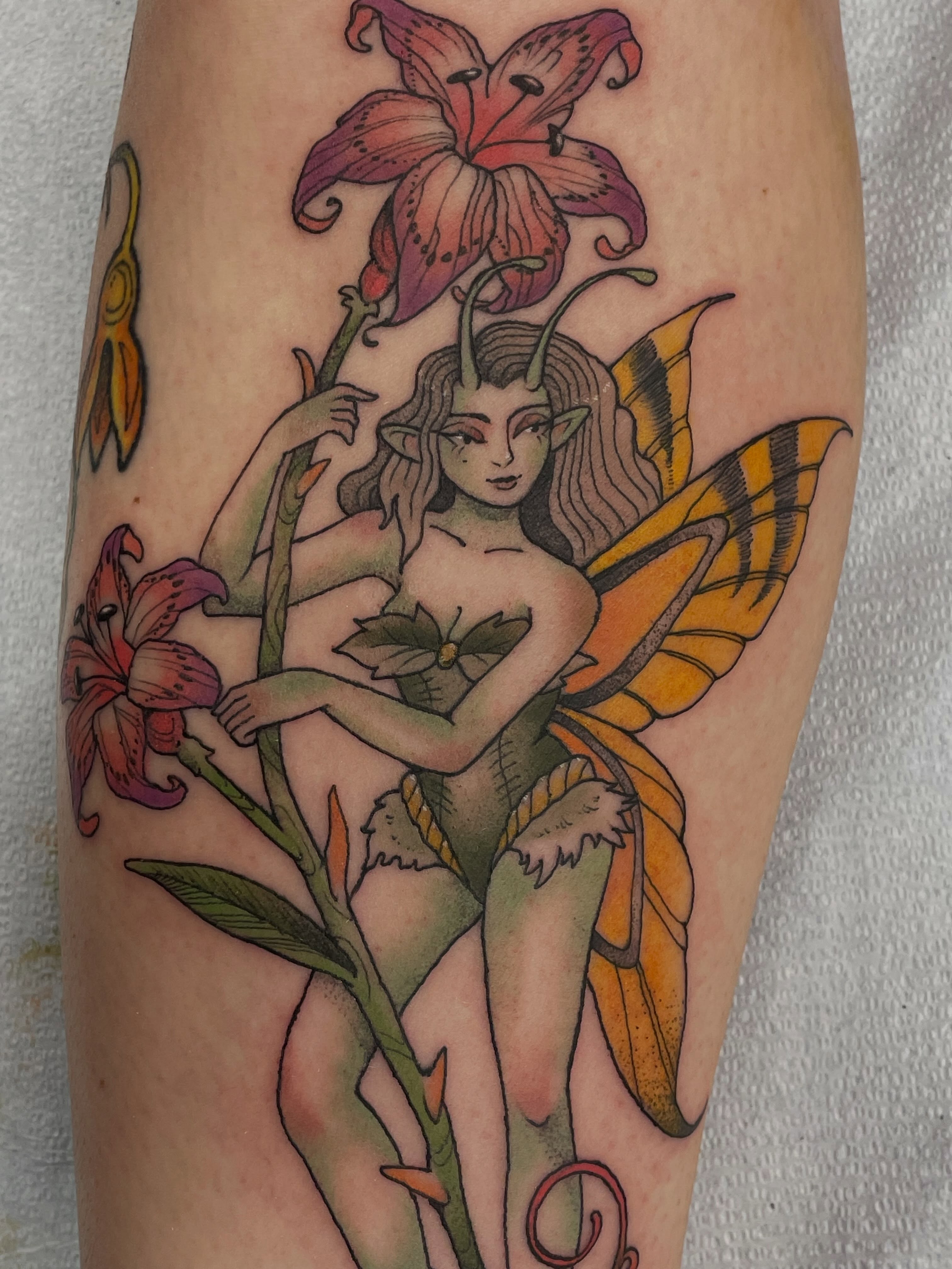 Fairy with lilies new school tattoo on the forearm by Fionna Fanning