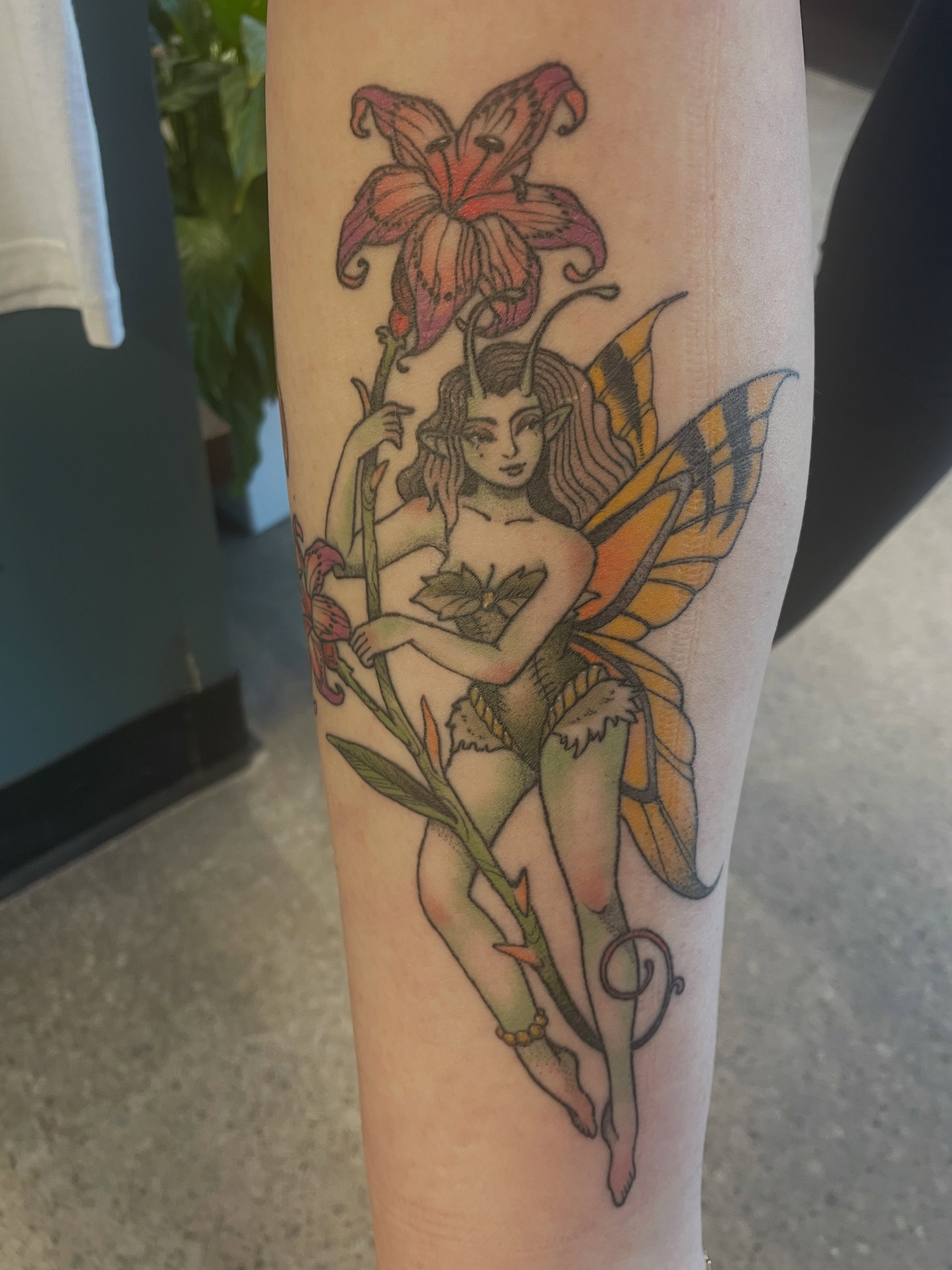 Fairy with lily new school tattoo on the forearm by Fionna Fanning