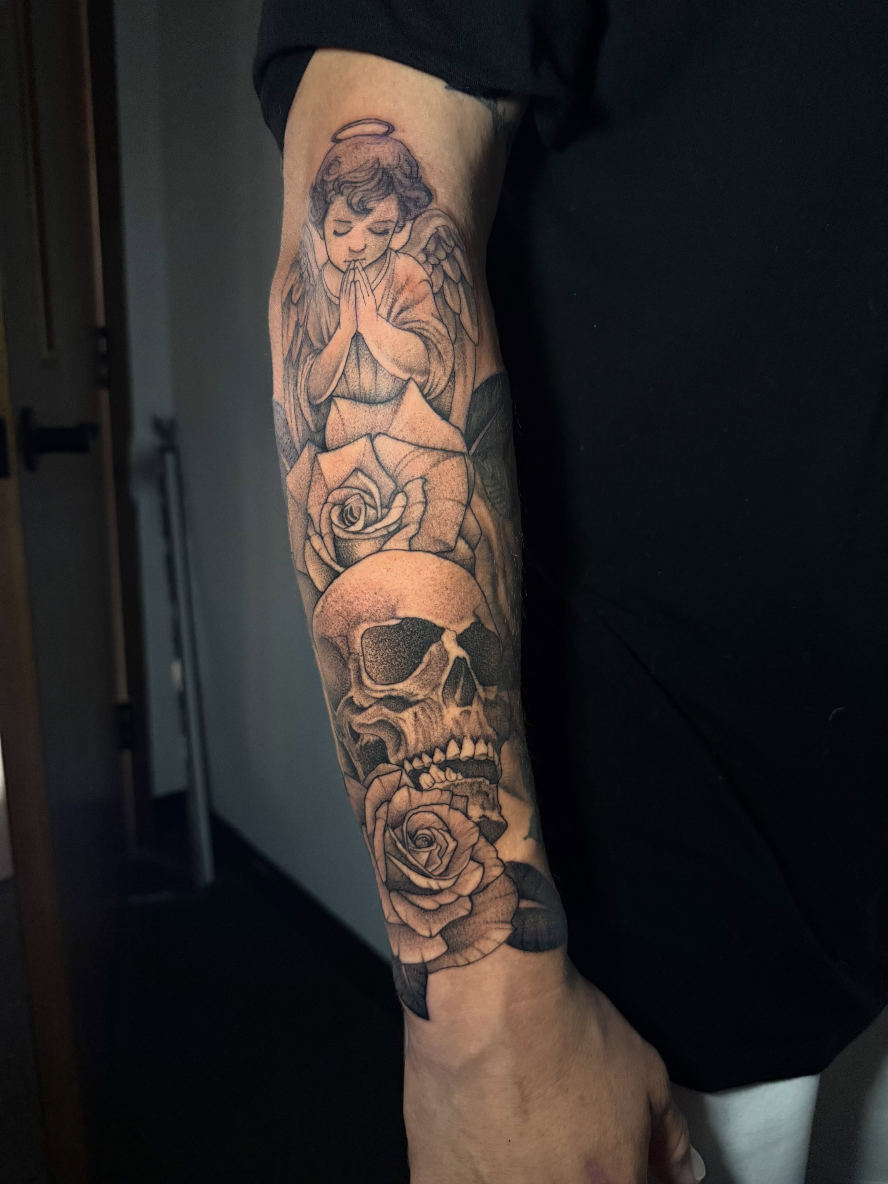Praying angel with roses and skull realism tattoo on the forearm by Lindsay