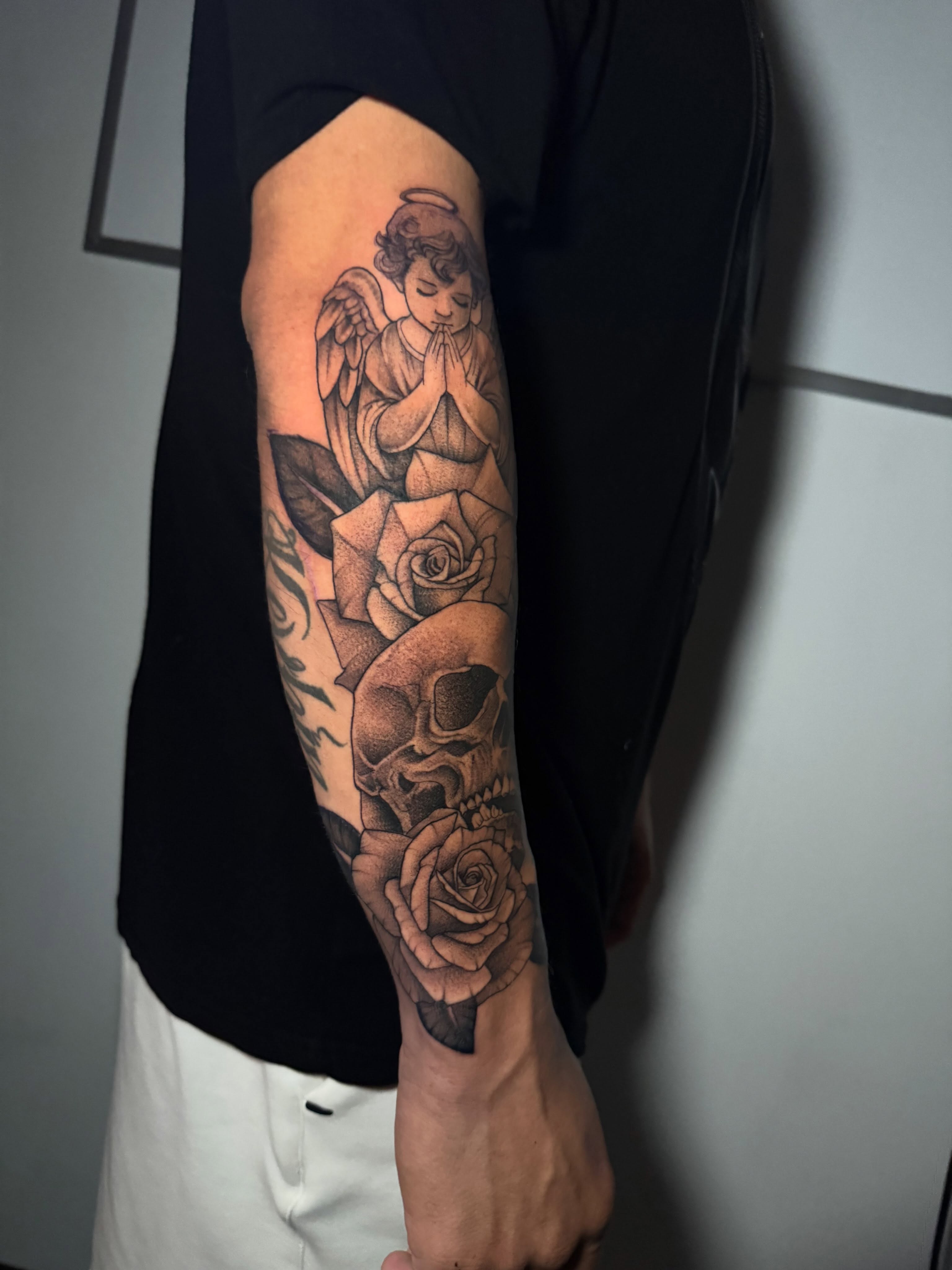 Angel with roses and skulls realism tattoo on the forearm by Lindsay