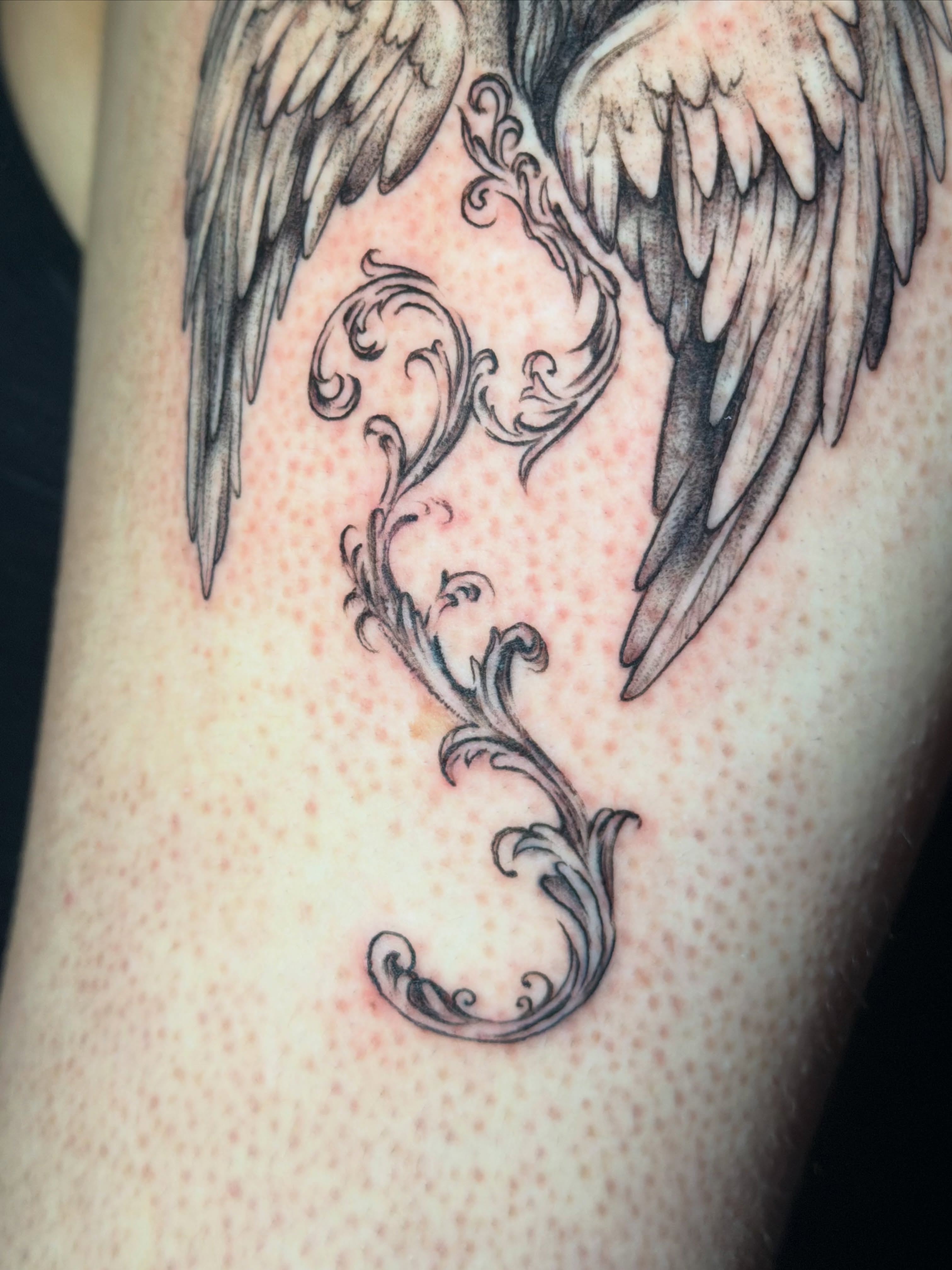 Wings and flourish black and grey tattoo on the forearm by tattoo artist (mollz)