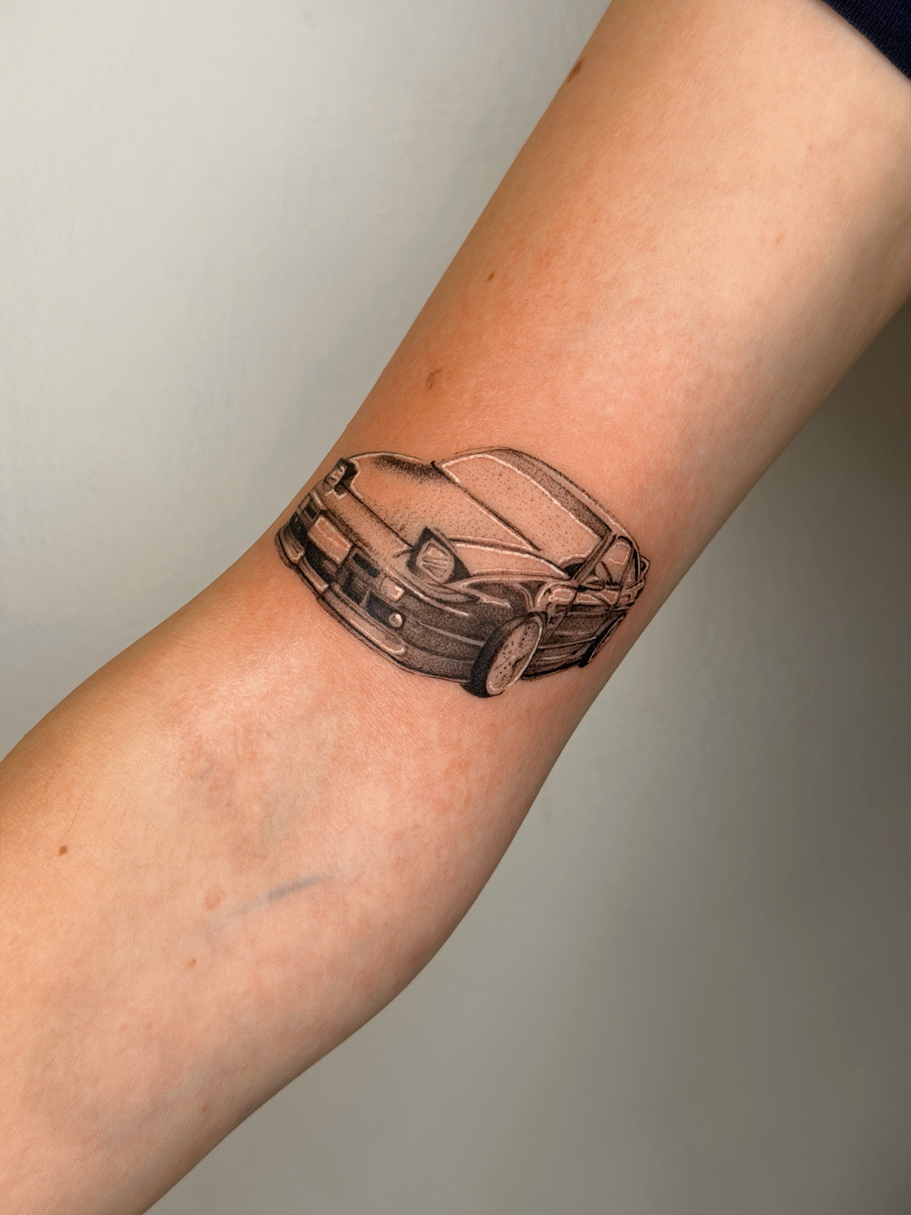 Car black and grey tattoo on the forearm by Nate Weaver