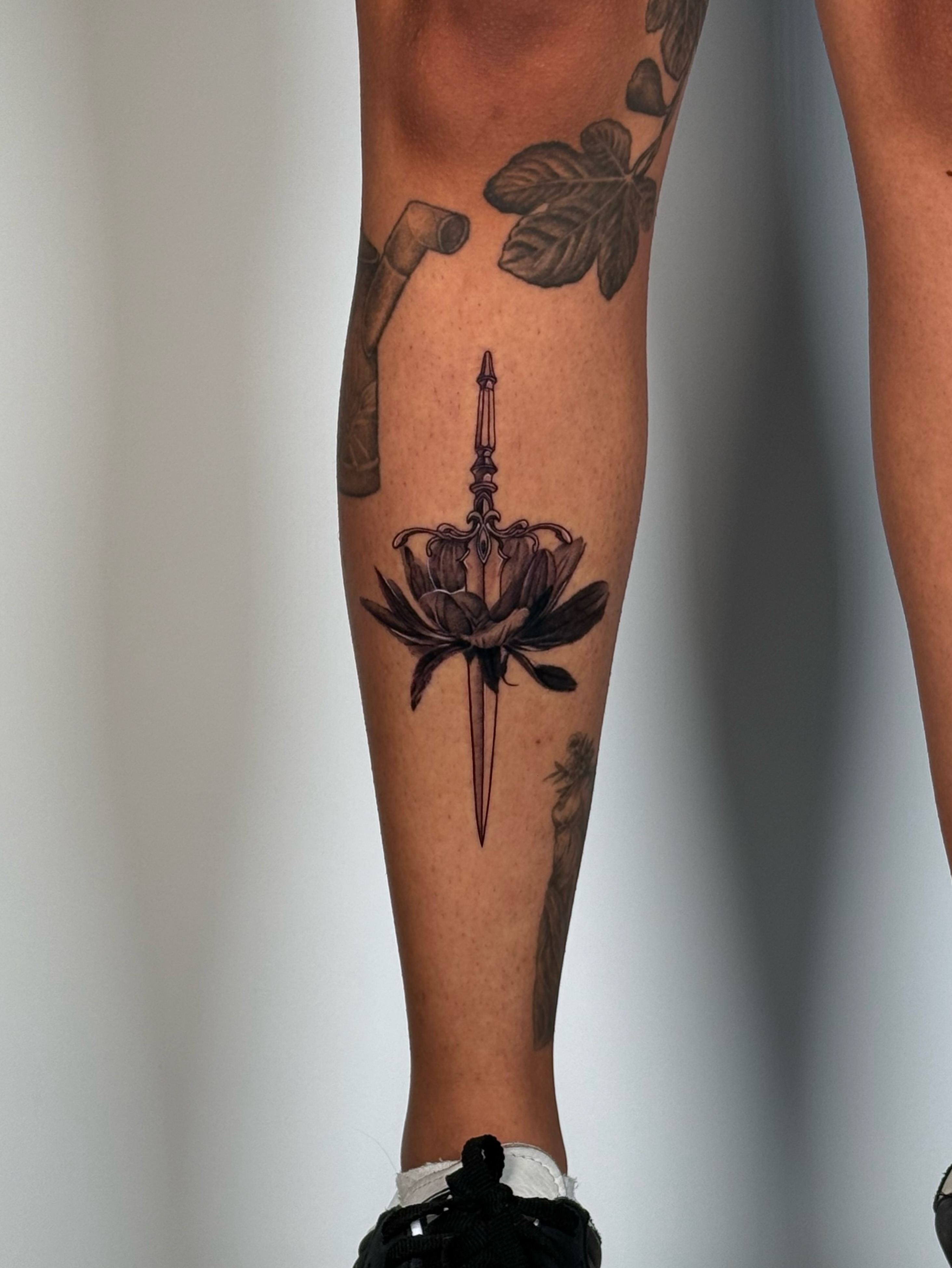 Lotus flower with dagger realism tattoo on the calf by jaz🌀