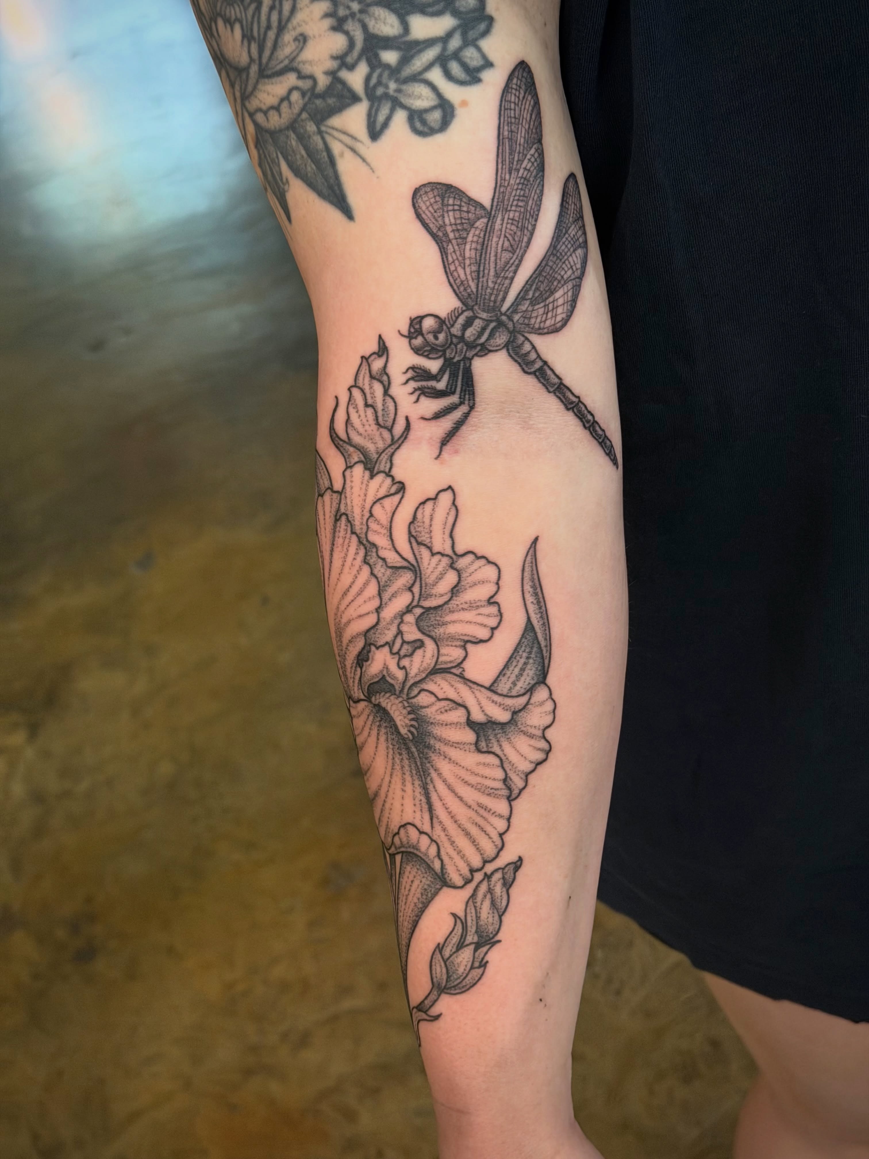 Dragonfly and flowers black and grey tattoo on the forearm by Thad Collis