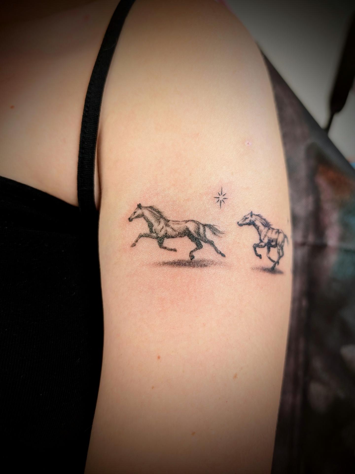 Horses black and grey tattoo on the upper arm by Rhiannon