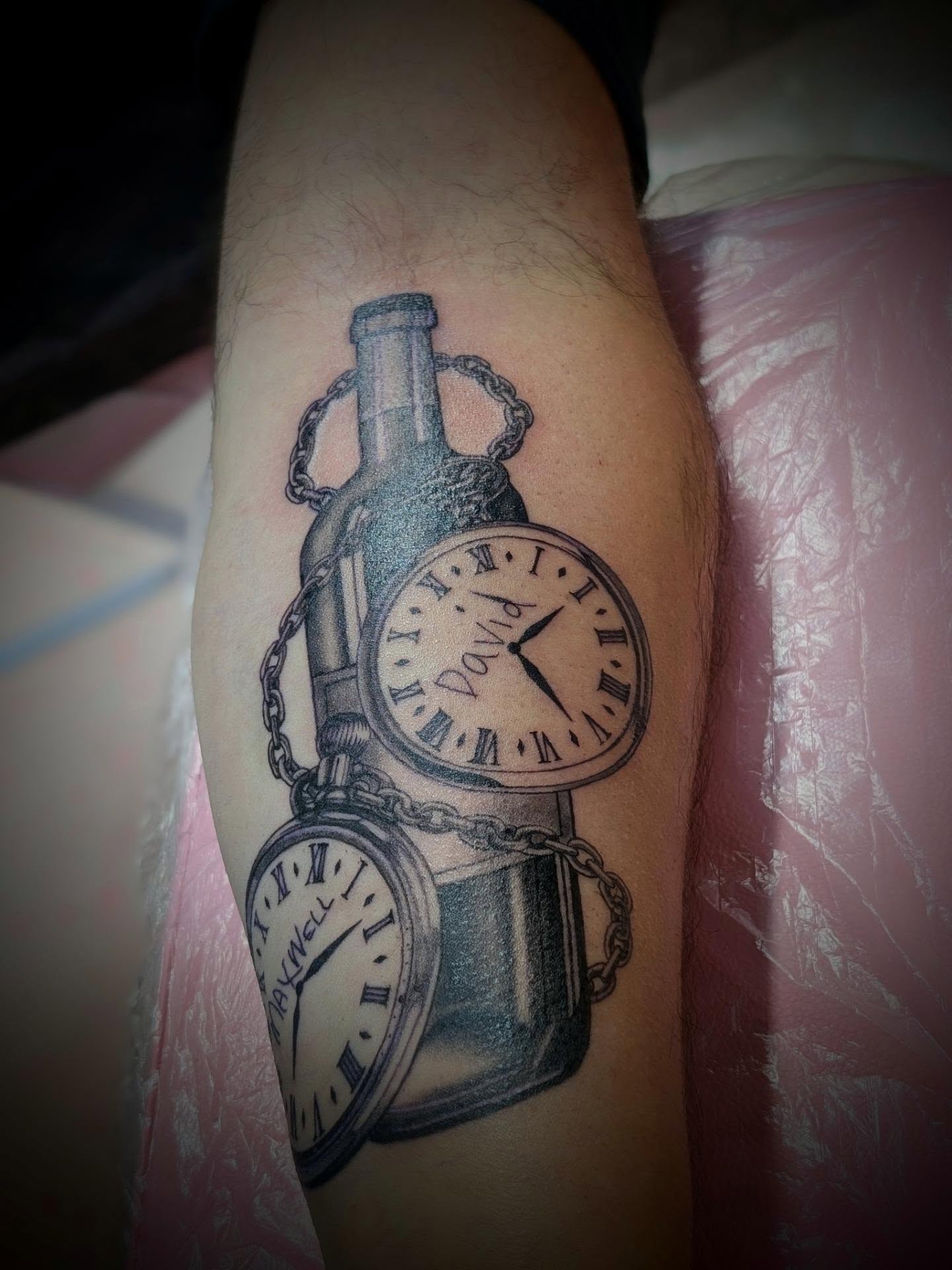 Clock and bottle black and grey tattoo on the forearm by Rhiannon