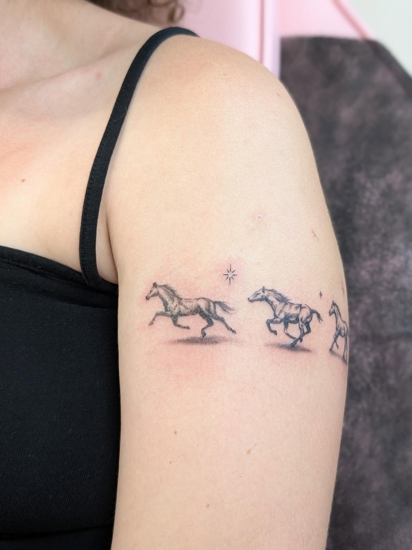 Horses black and grey tattoo on the upper arm by Rhiannon