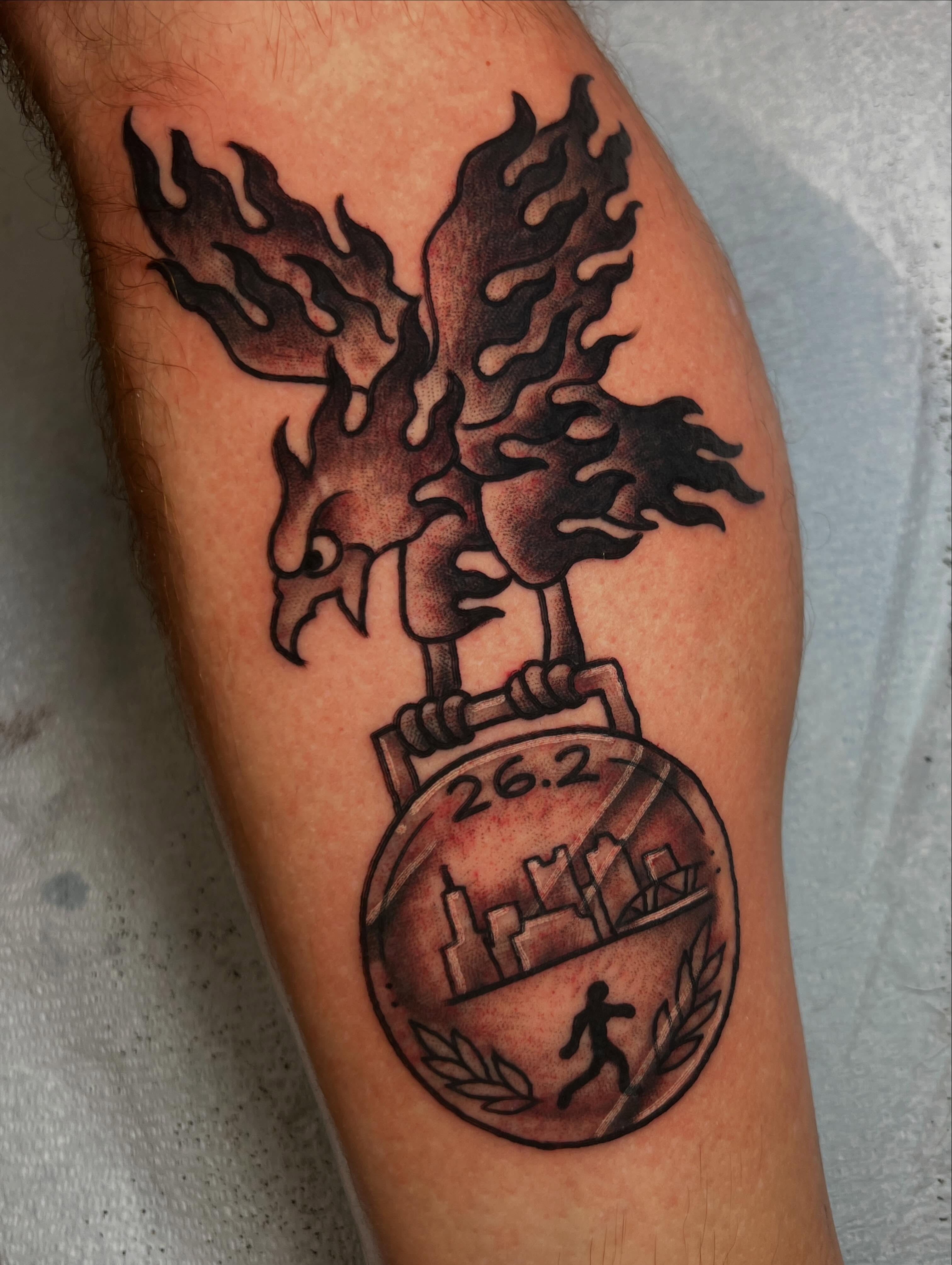 Flaming bird with medal black and grey tattoo on the forearm by Mat Helton, Fairborn, Ohio