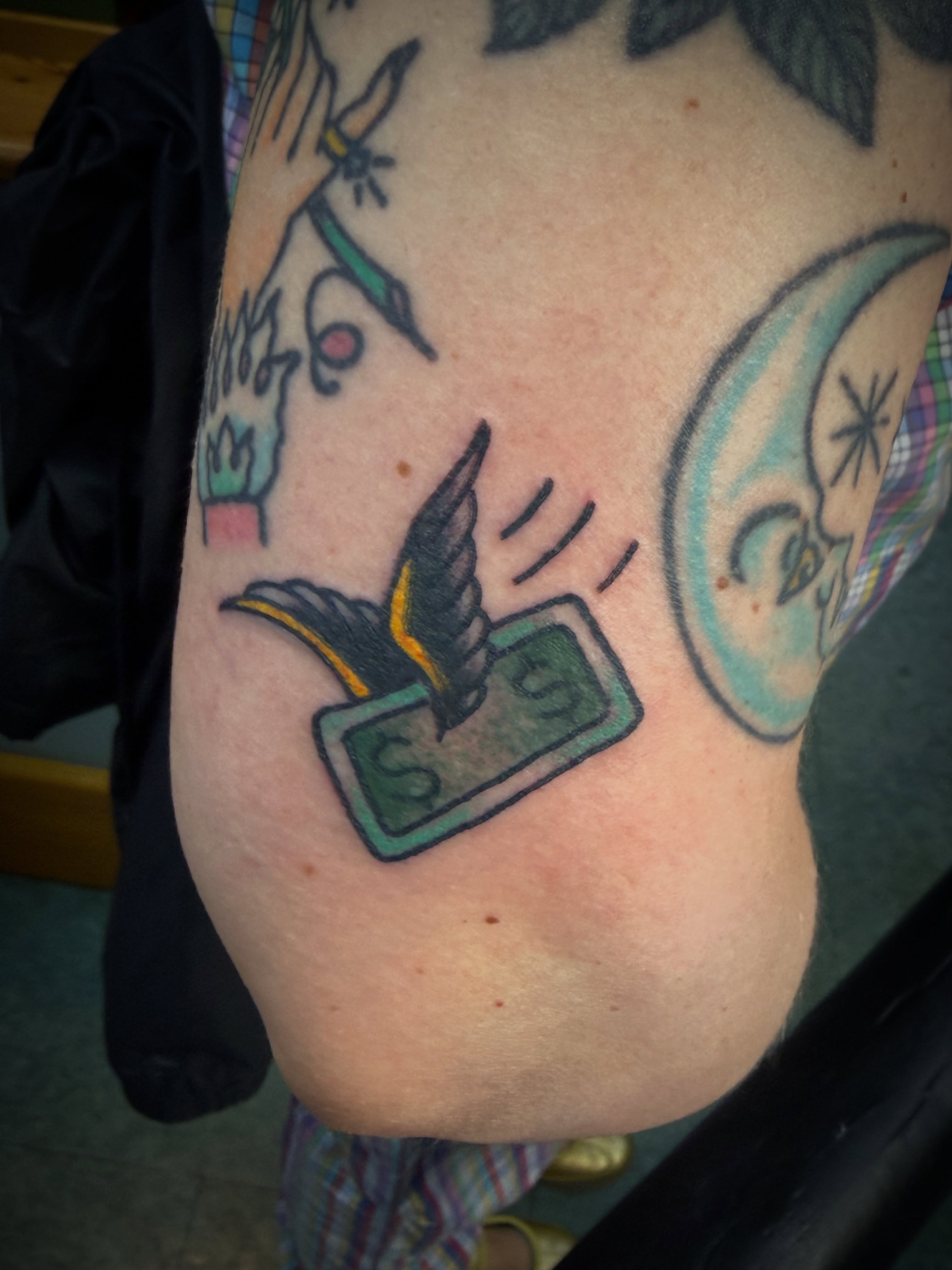 Money bird American traditional tattoo on the upper arm by Chris Blanchard