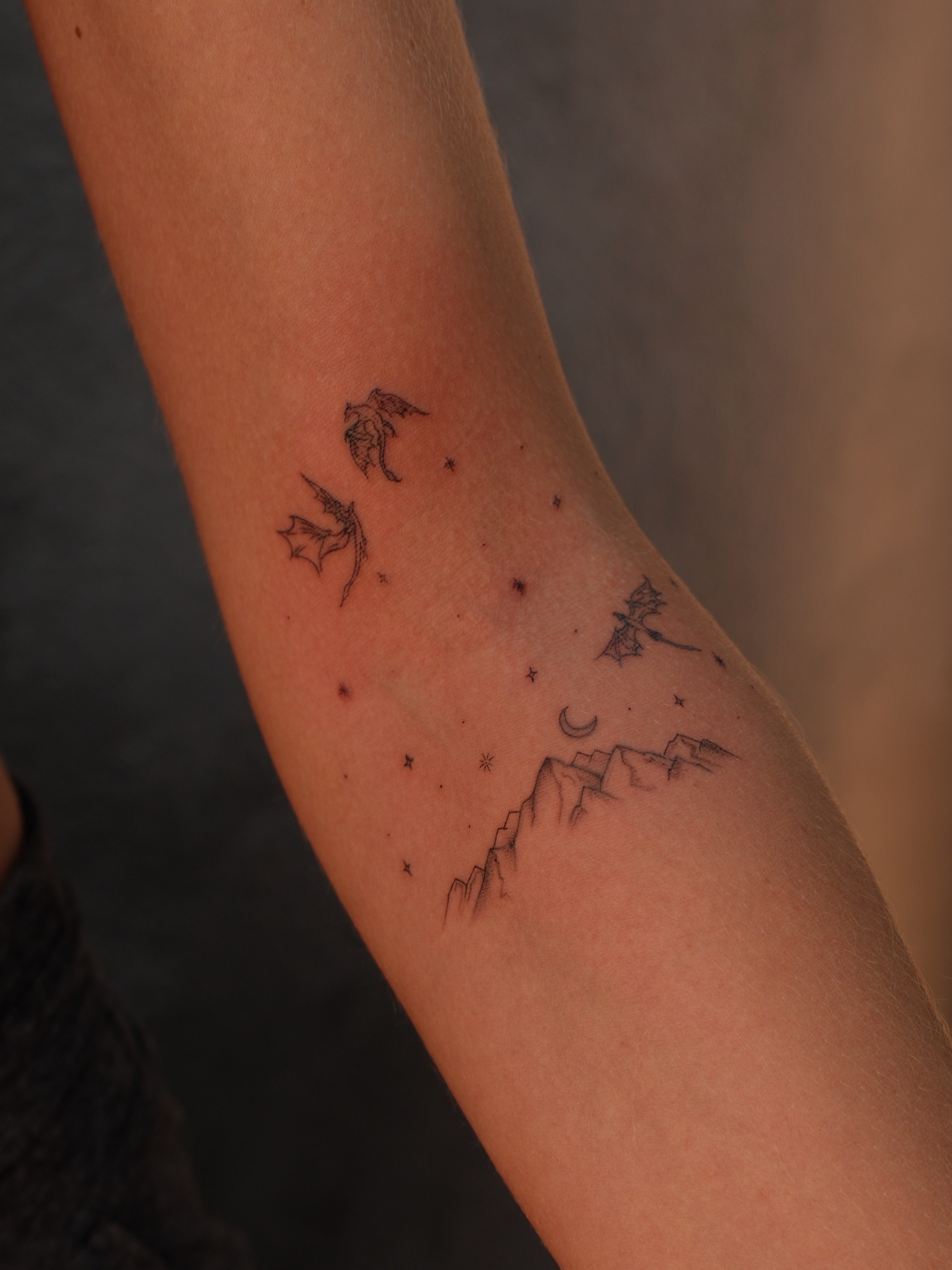 Mountain range and stars minimalist tattoo on the forearm by Luisa Duarte