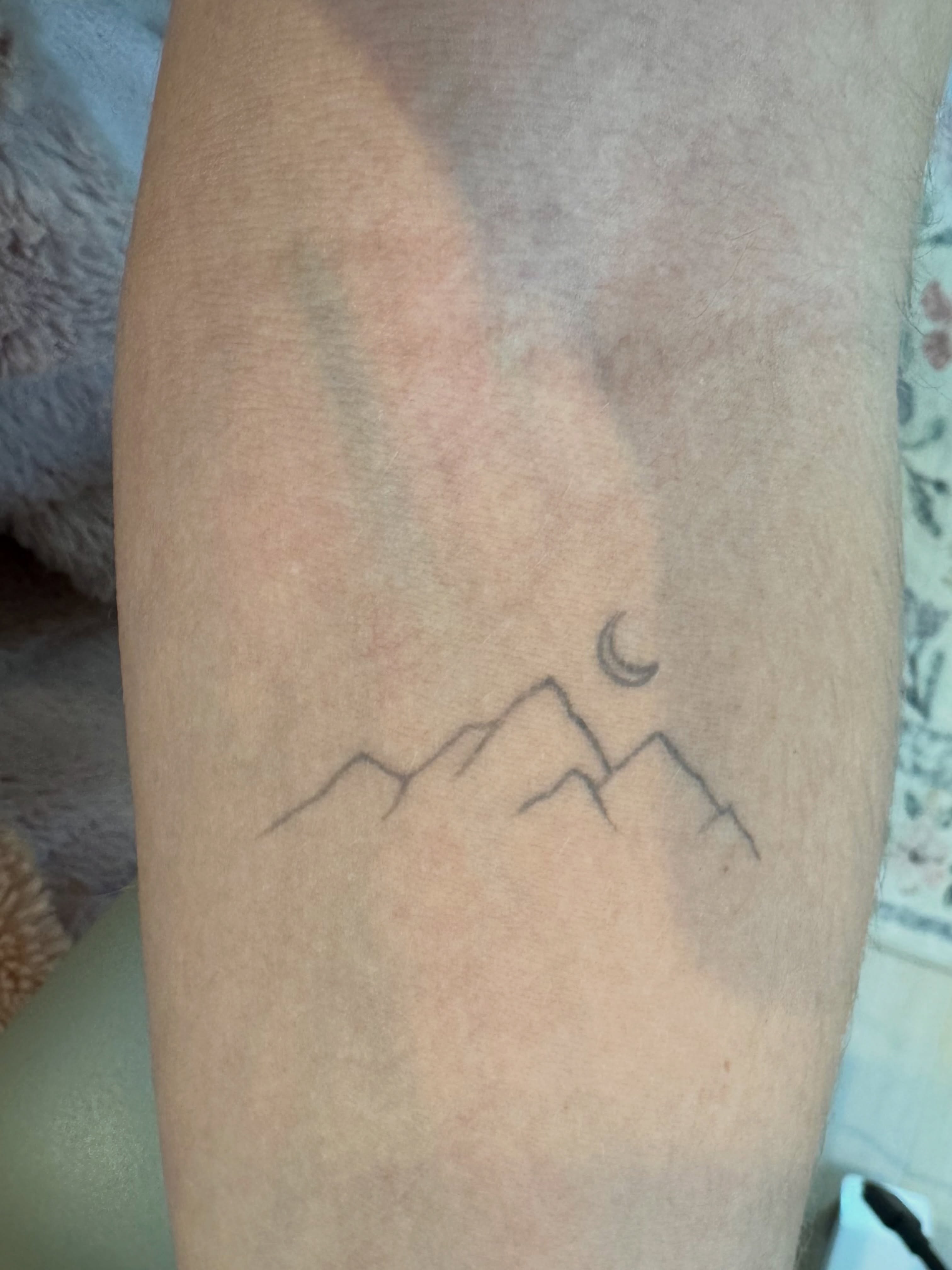 Mountains and crescent moon minimalist tattoo on the forearm by Luisa Duarte