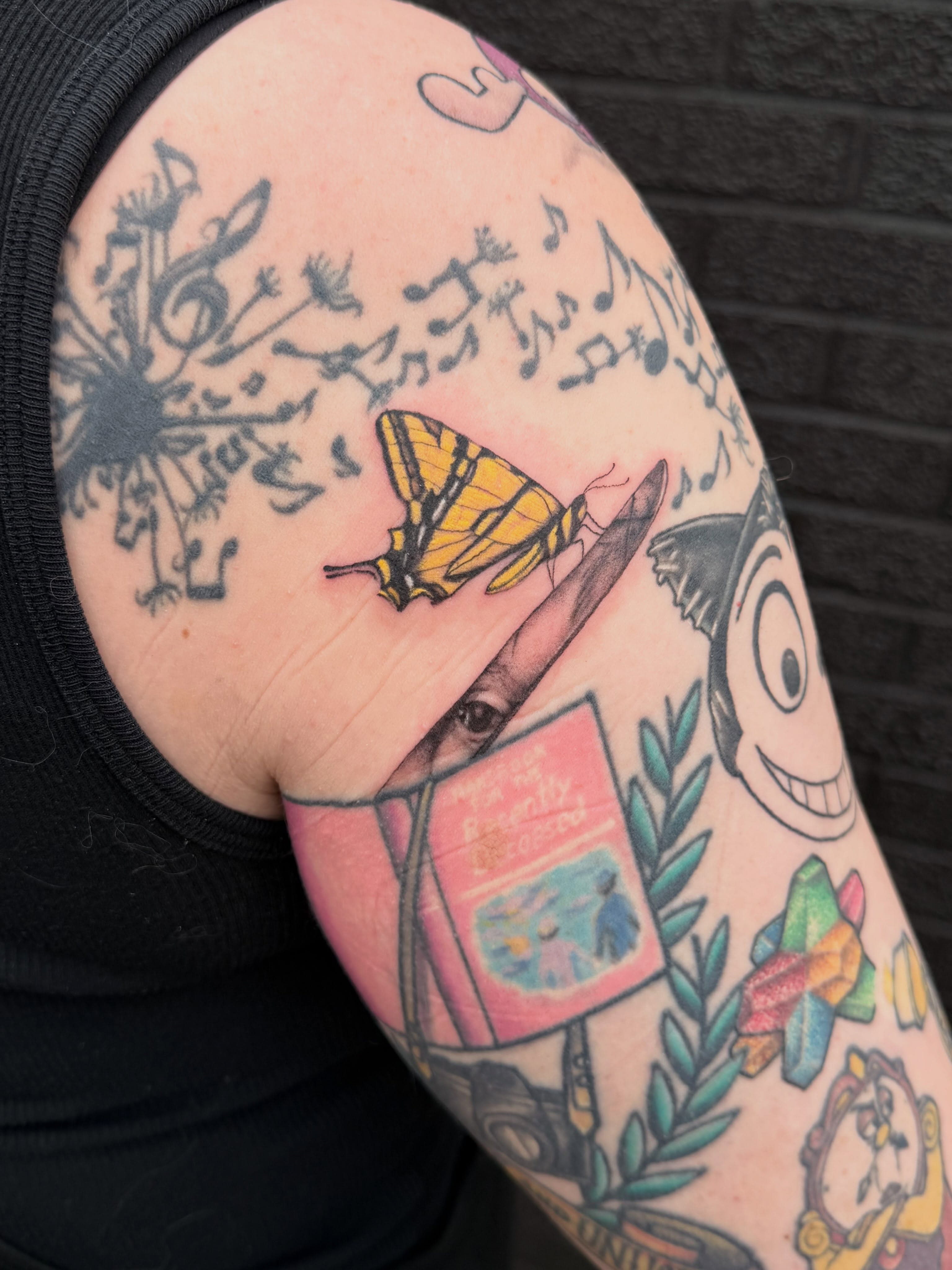 Butterfly and book American traditional tattoo on the upper arm by Shelly Elissa Tattoos