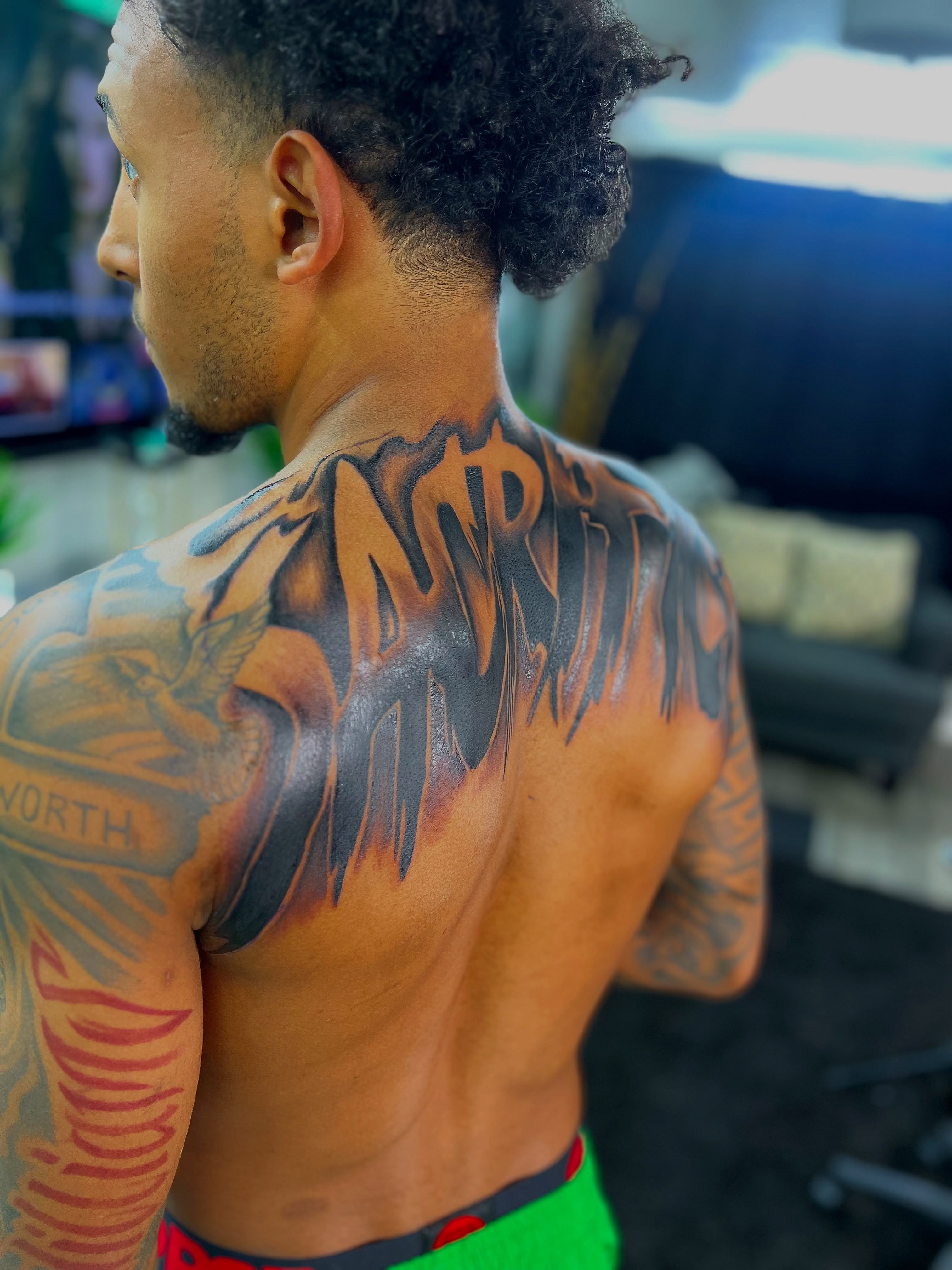Wings and text American traditional tattoo on the back by Deonte Dwayne Durham