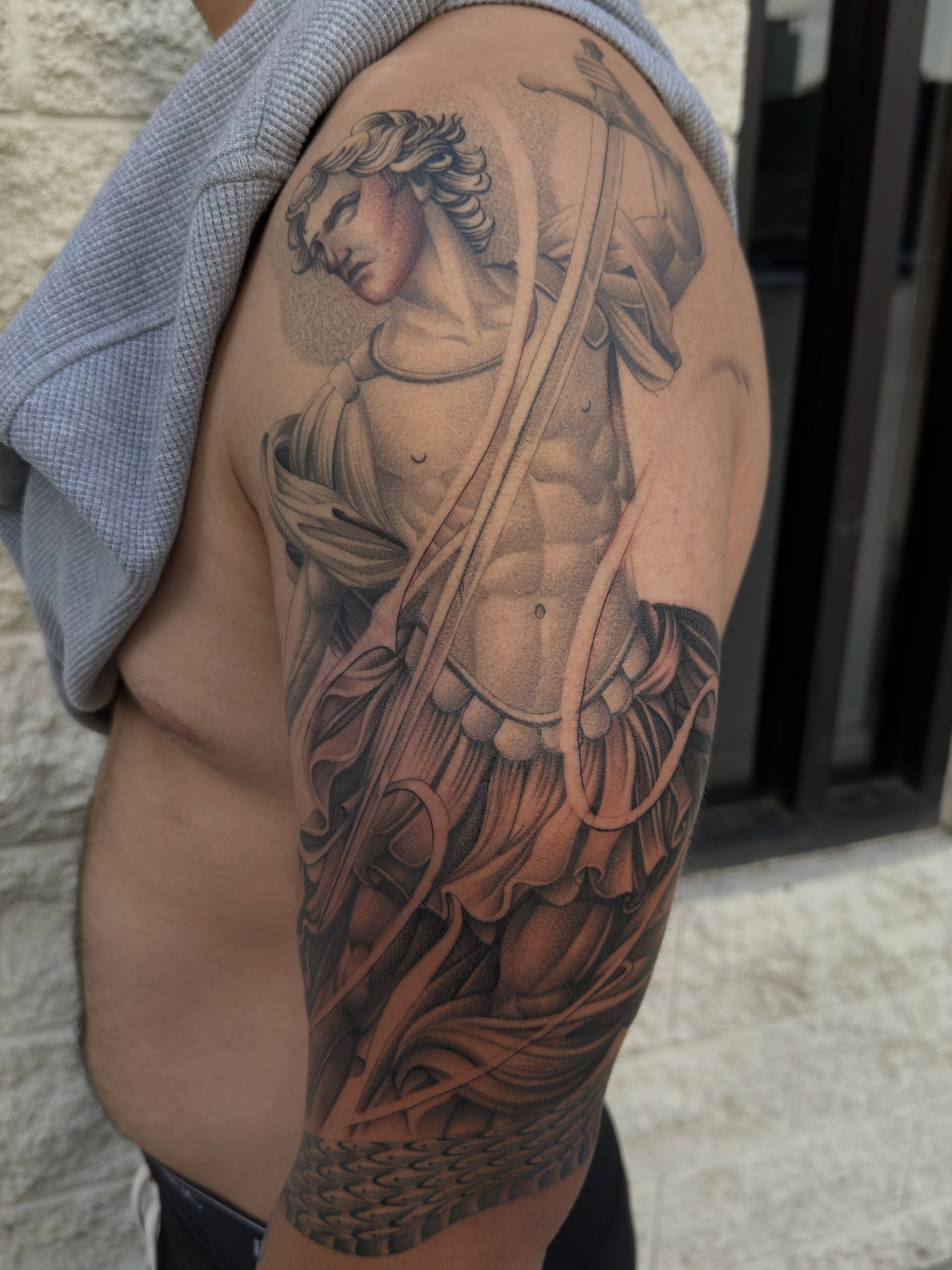 Statue of a warrior realism tattoo on the upper arm by San Diego Tattoo Artist