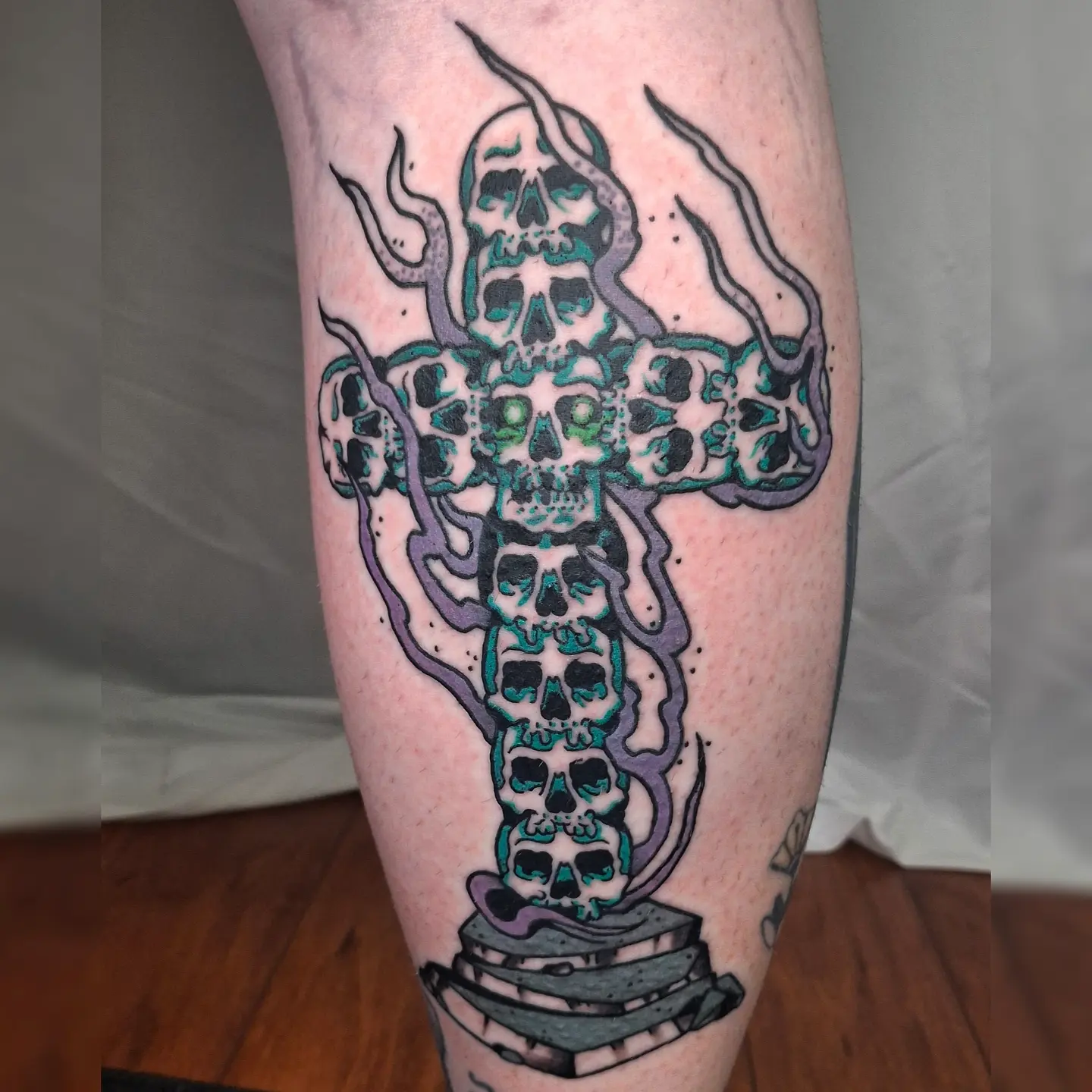 Skulls and cross neo-traditional tattoo on the calf by Jake Mincey