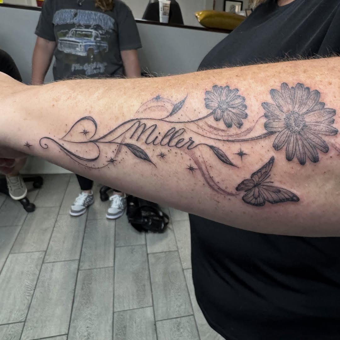 Daisies and butterfly black and grey tattoo on the forearm by Joey Flaherty