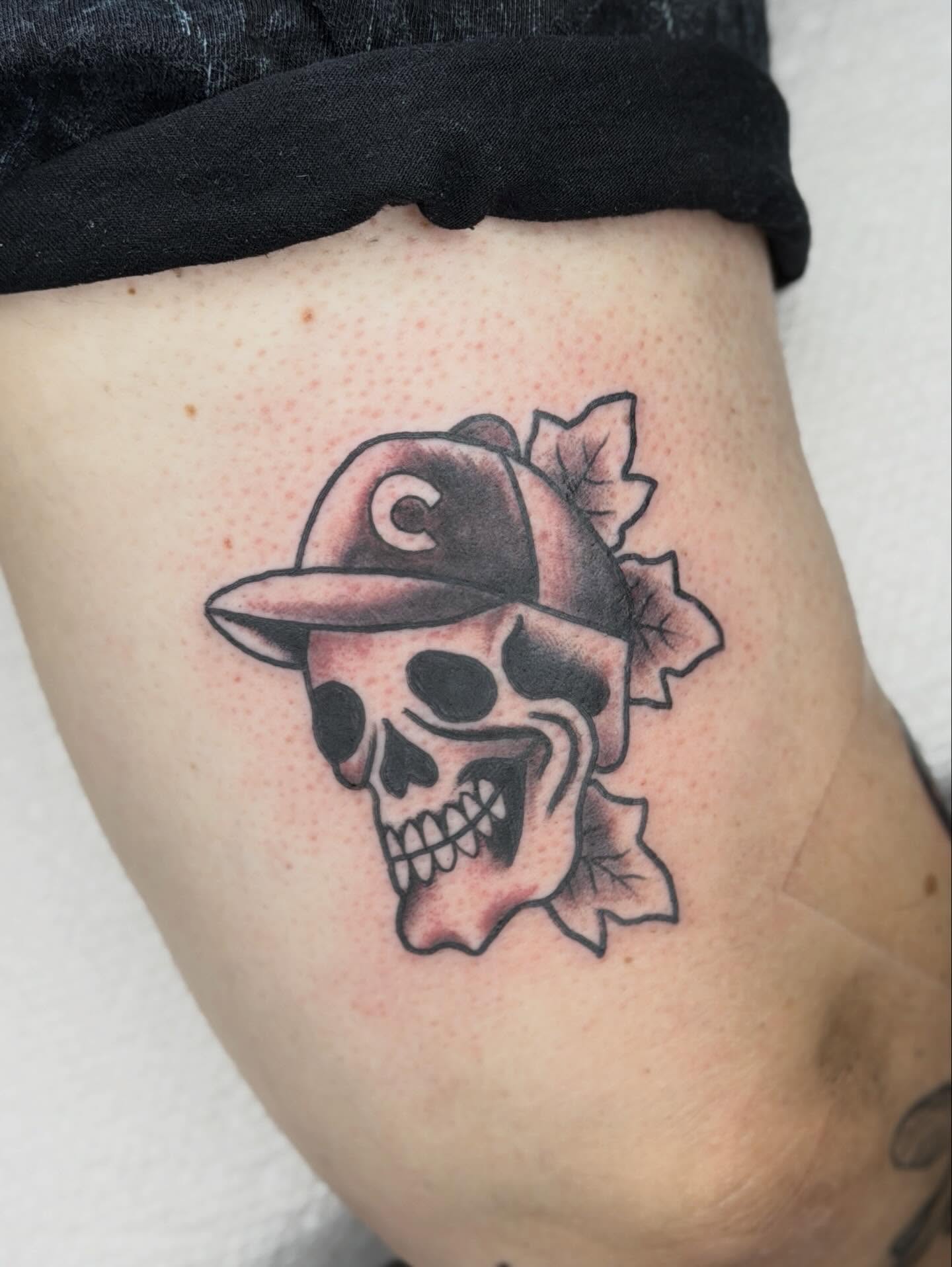 Skull wearing cap black and grey tattoo on the thigh by Jenna Szerszen-Wynn ๐