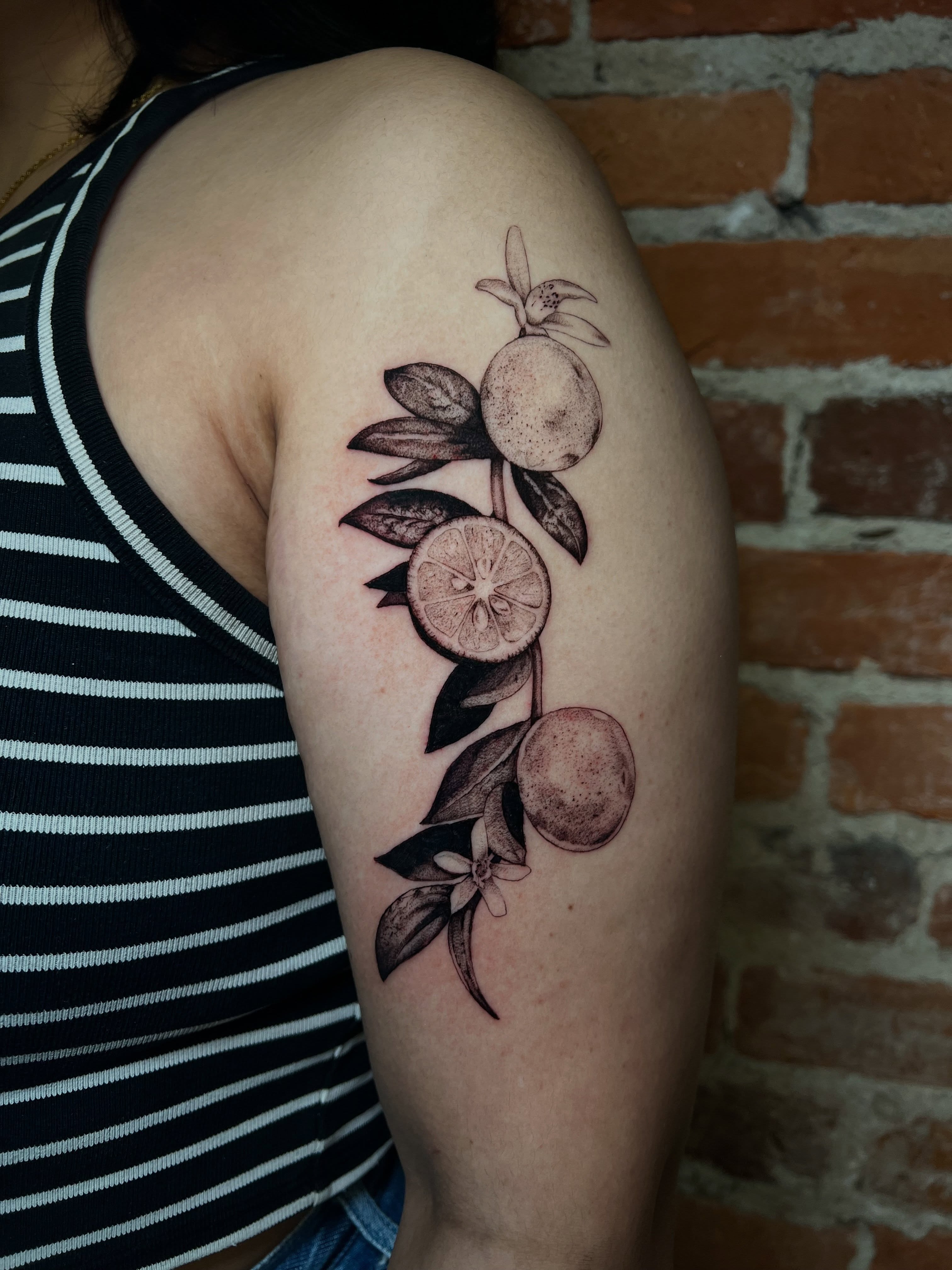 Fruit branch black and grey tattoo on the upper arm by Uncomfy Comfort Tattoos LLC
